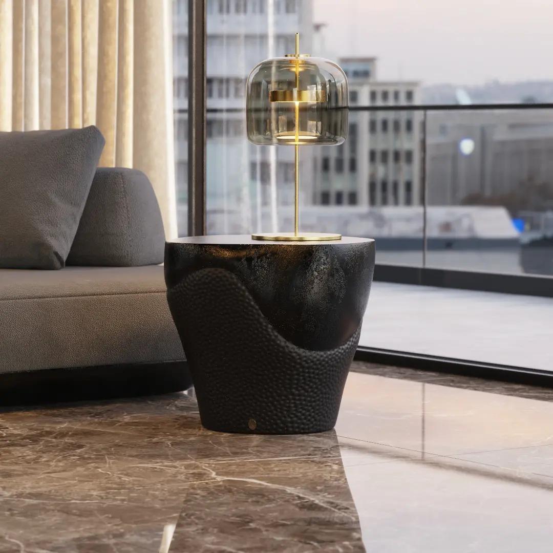 Rodea tu espacio con la moderna elegancia de esta mesa de centro con acabado en bronce que añade un toque de lujoso refinamiento. El diseño único de esta mesa auxiliar trasciende los límites tradicionales, ofreciendo una pieza contemporánea que