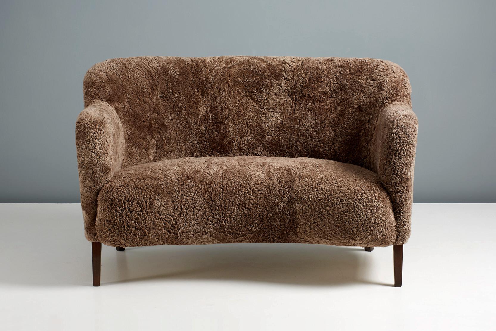 A custom-made new edition of this classic love-seat sofa by Danish designer and cabinetmaker: Alfred Kristensen. This re-edition is produced under license in Sweden by Dagmar and available to order in a range of upholstery and wood finishes.