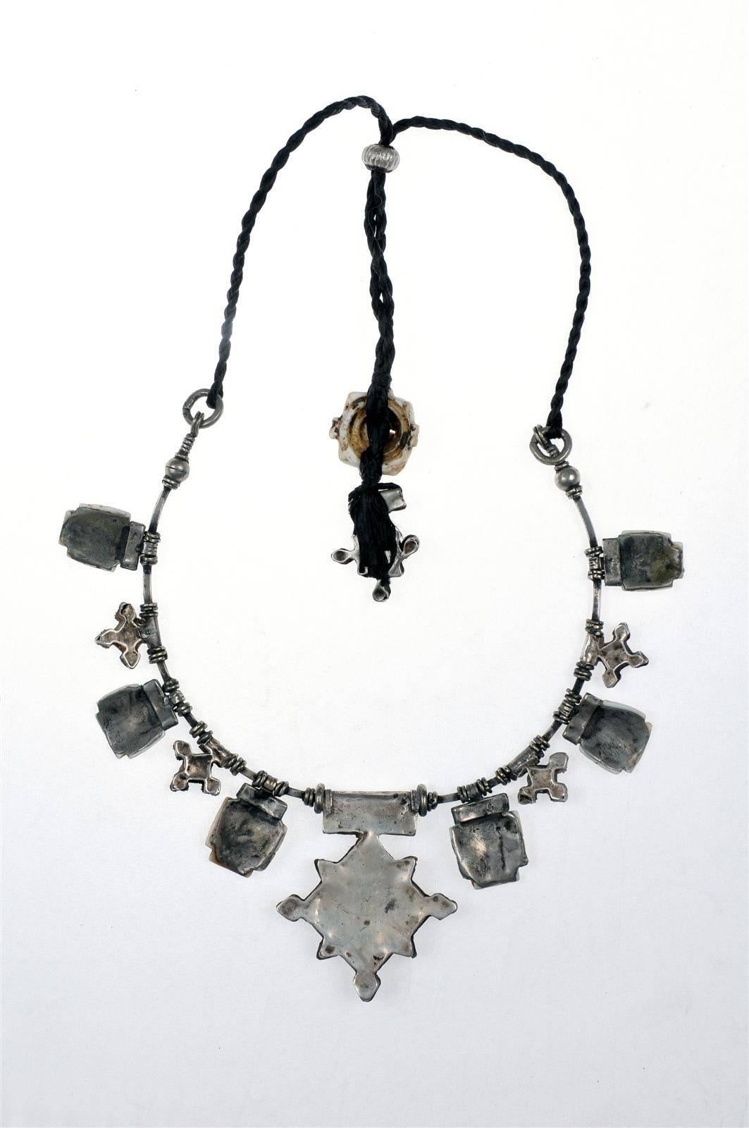 A custom made necklace by Famous Moroccan jeweler Chez Faouzi of Marrakech. Necklace is made of antique Moroccan silver and conus shell charms with the signature Faouzi back neck charm. Black chord is adjustable to 35.