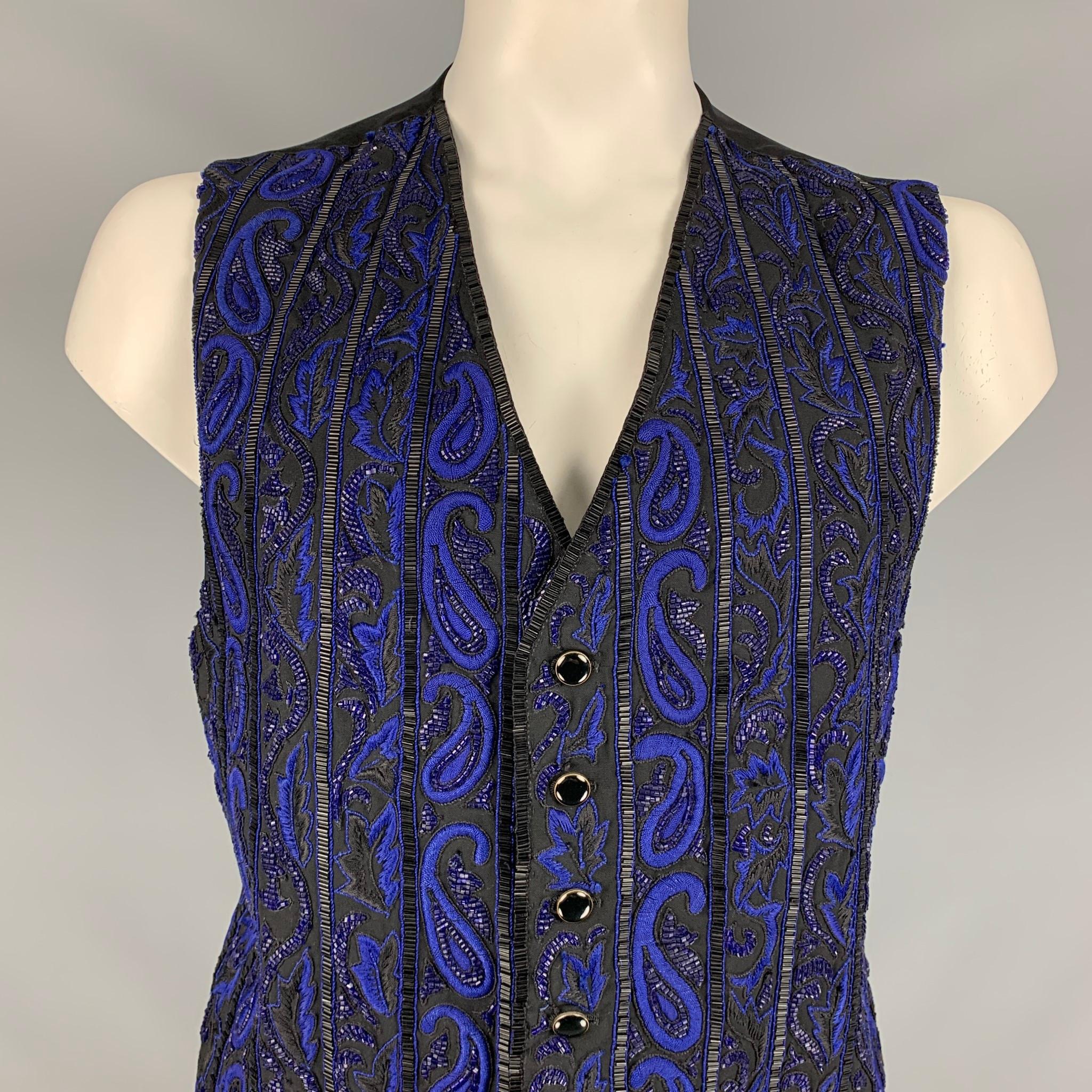 CUSTOM MADE vest comes in a black & blue beaded material featuring a back belt and a buttoned closure. 

Very Good Pre-Owned Condition. Fabric tag removed.
Marked: Size tag removed.

Measurements:

Shoulder: 15 in.
Chest: 40 in.
Length: 21 in. 