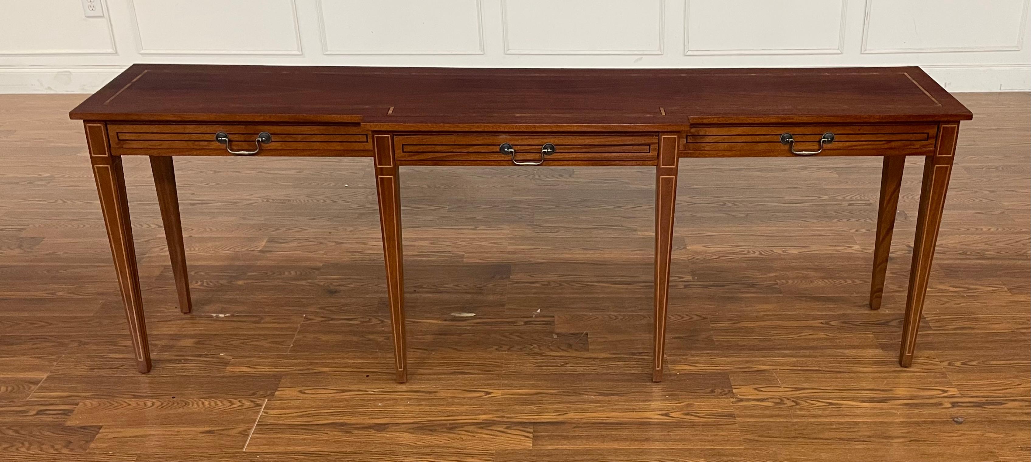 This a custom Hepplewhite style mahogany console/sofa table. It is made-to-order in the Leighton Hall shop in Suwanee, Georgia.  It features classic Hepplewhite styling with square tapered and inlaid legs, a cathedral mahogany top with Movingue