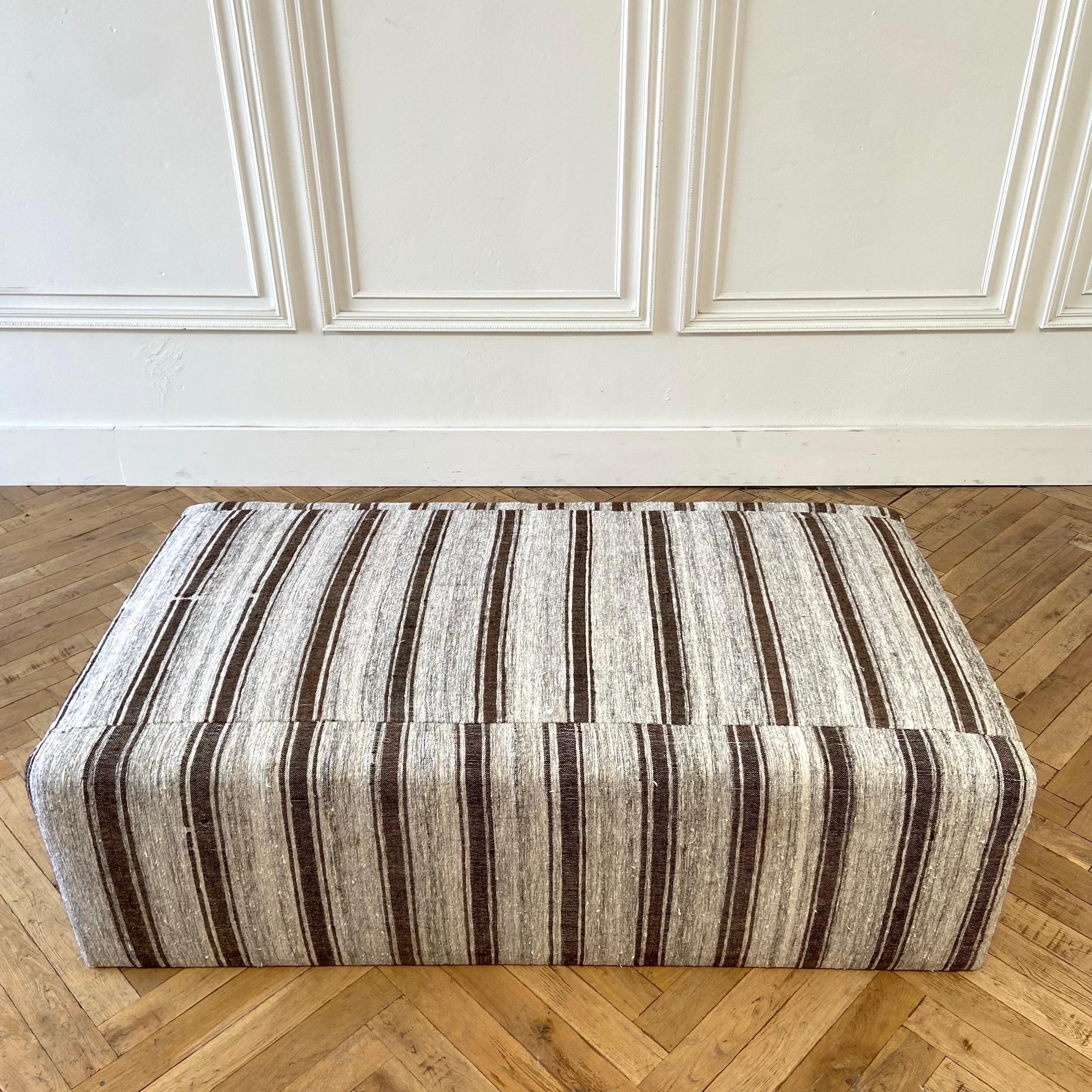 Custom made cube style cocktail ottoman.
Made from a vintage turkish wool rug, in oyster, gray and dark brown stripes.
The base is made from wood, with a generous HR foam top. This foam is firm, great to use as a coffee table, but also can second