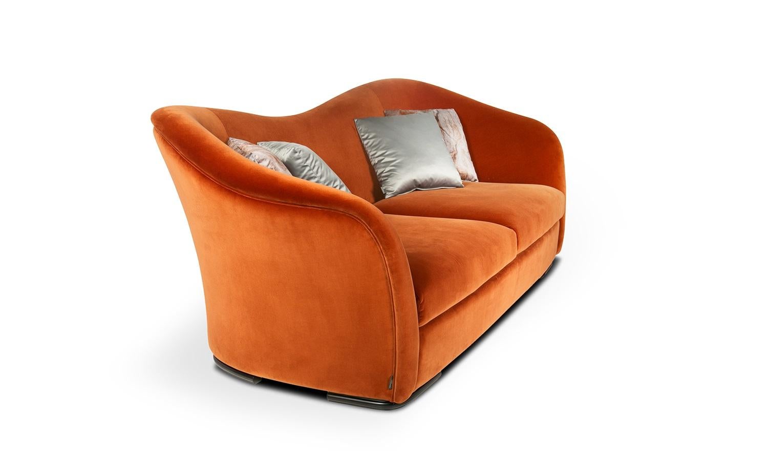 Ein zeitgemäßes Sofa, das Elemente der Klassiker enthält. Die sanft geschwungene Rückenlehne bietet mehr Halt und geht fließend in die Armlehnen über. Gestell und Sockel aus Massivholz in Espresso-Optik. 
Vier Kissen sorgen für zusätzlichen