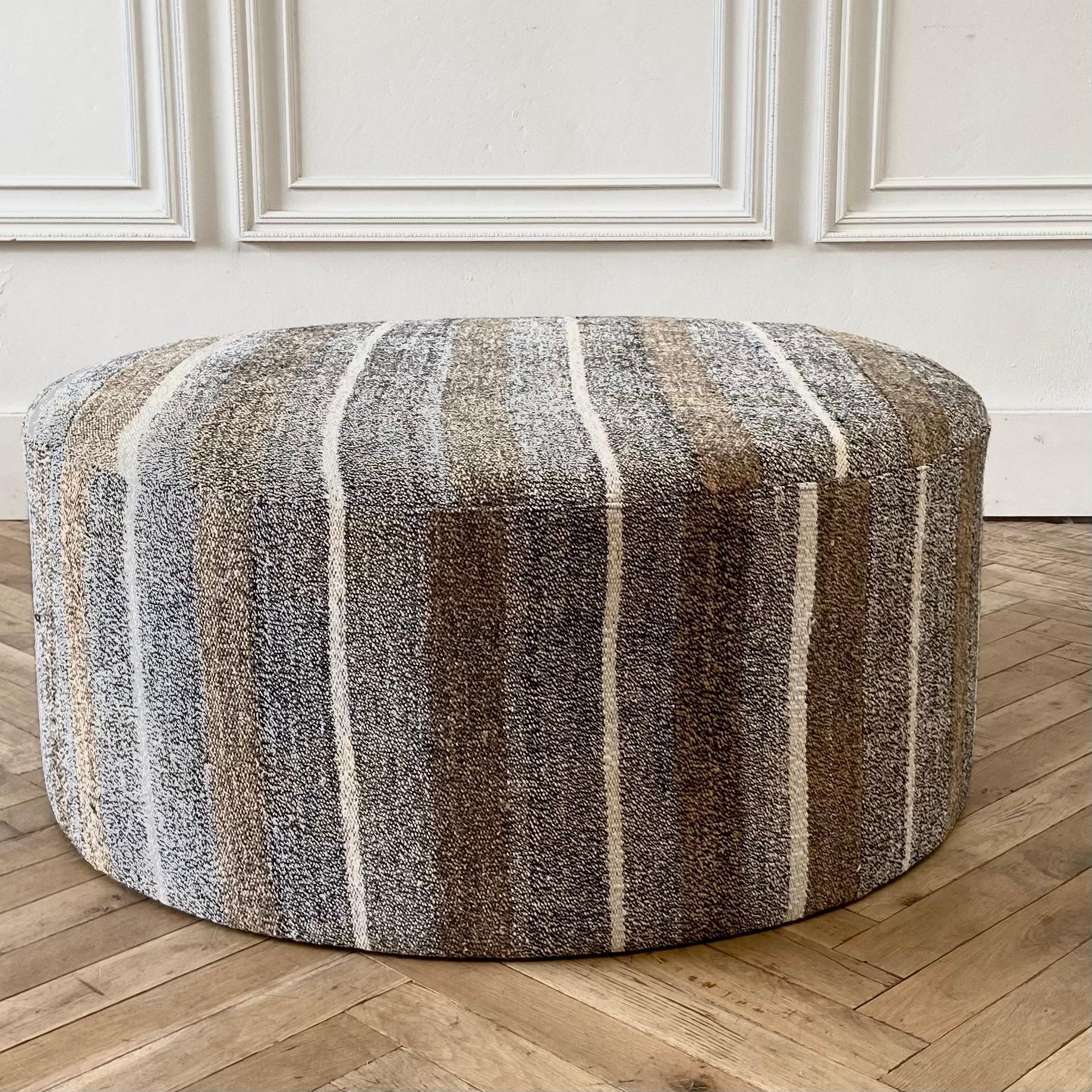 Custom made vintage Turkish rug round cocktail ottoman coffee table 
Measures: 41? round x 17? height 
Once a stripe rug now a useful cocktail ottoman. Wool and goat hair rug in a greyish, brown, golden tones with white woven striped
