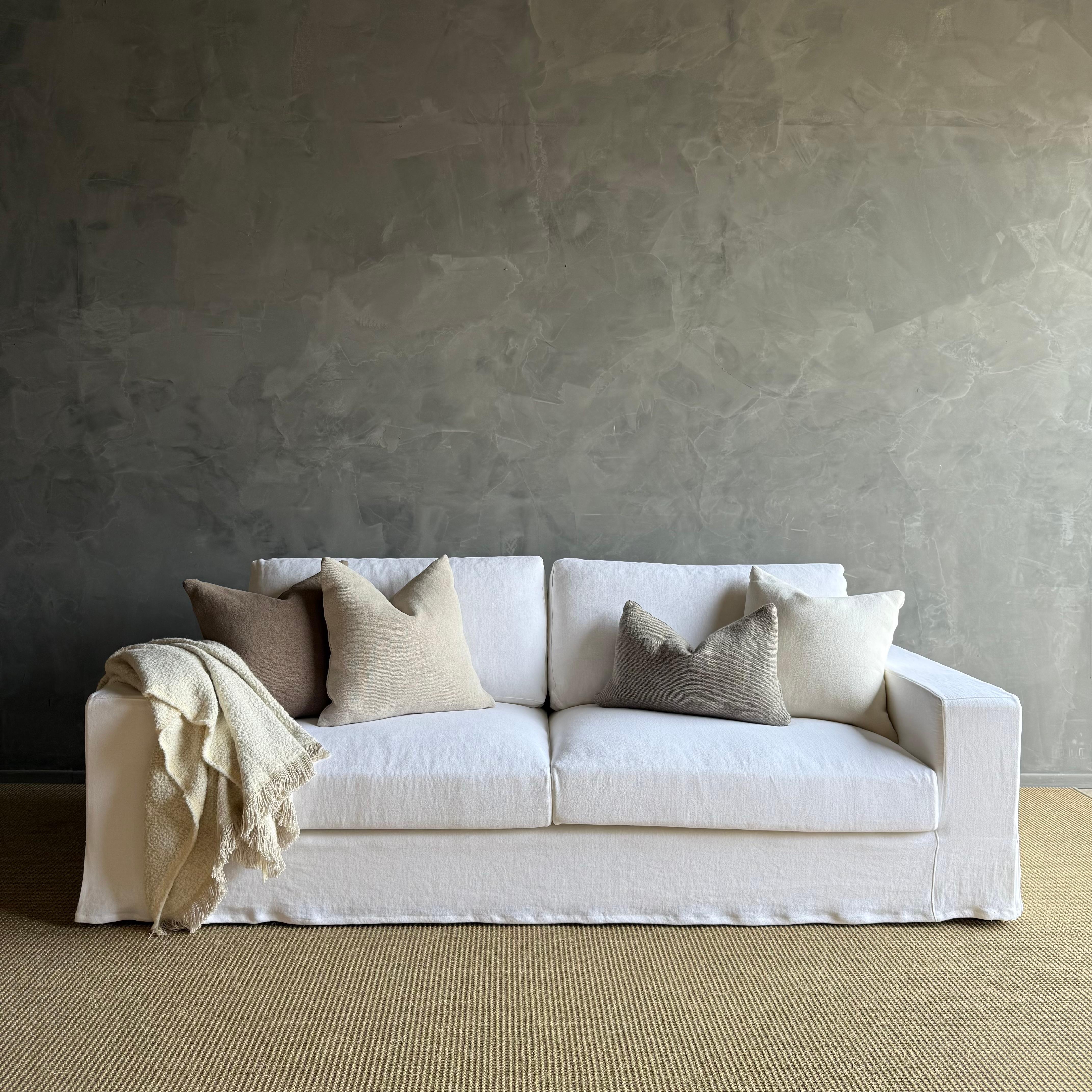 Introducing a slip-cover sofa crafted with Belgian white stone-washed linen, exuding a timeless elegance in any living space. The down cushions add a touch of luxury while ensuring maximum comfort for relaxing evenings. Ideal for both style and