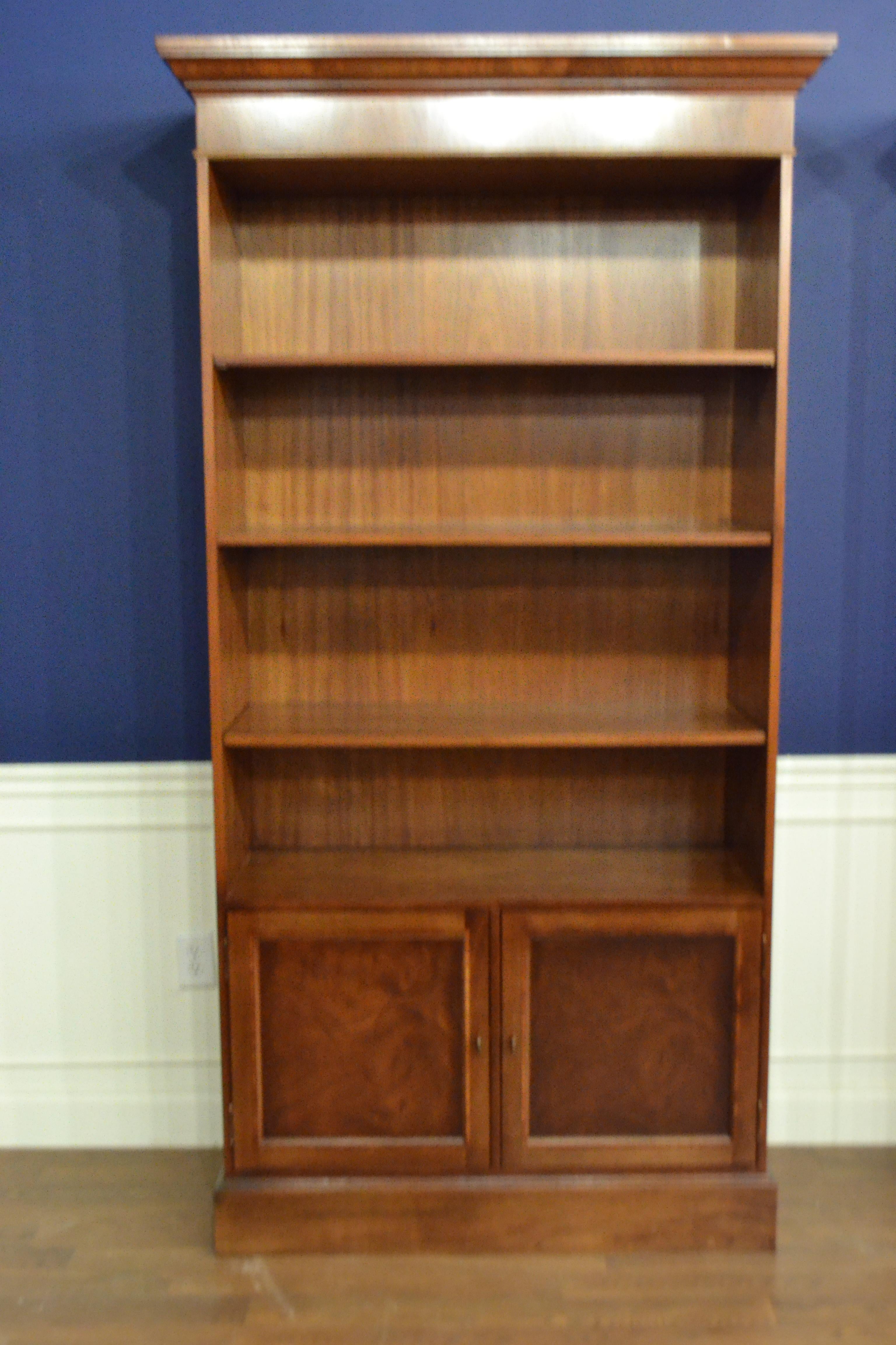 This is made-to-order traditional mahogany bookcase made in the Leighton Hall shop. It features two doors with swirly crotch mahogany fields and tulipwood inlays.. The top has one permanent shelf and two adjustable shelves. It features antique brass