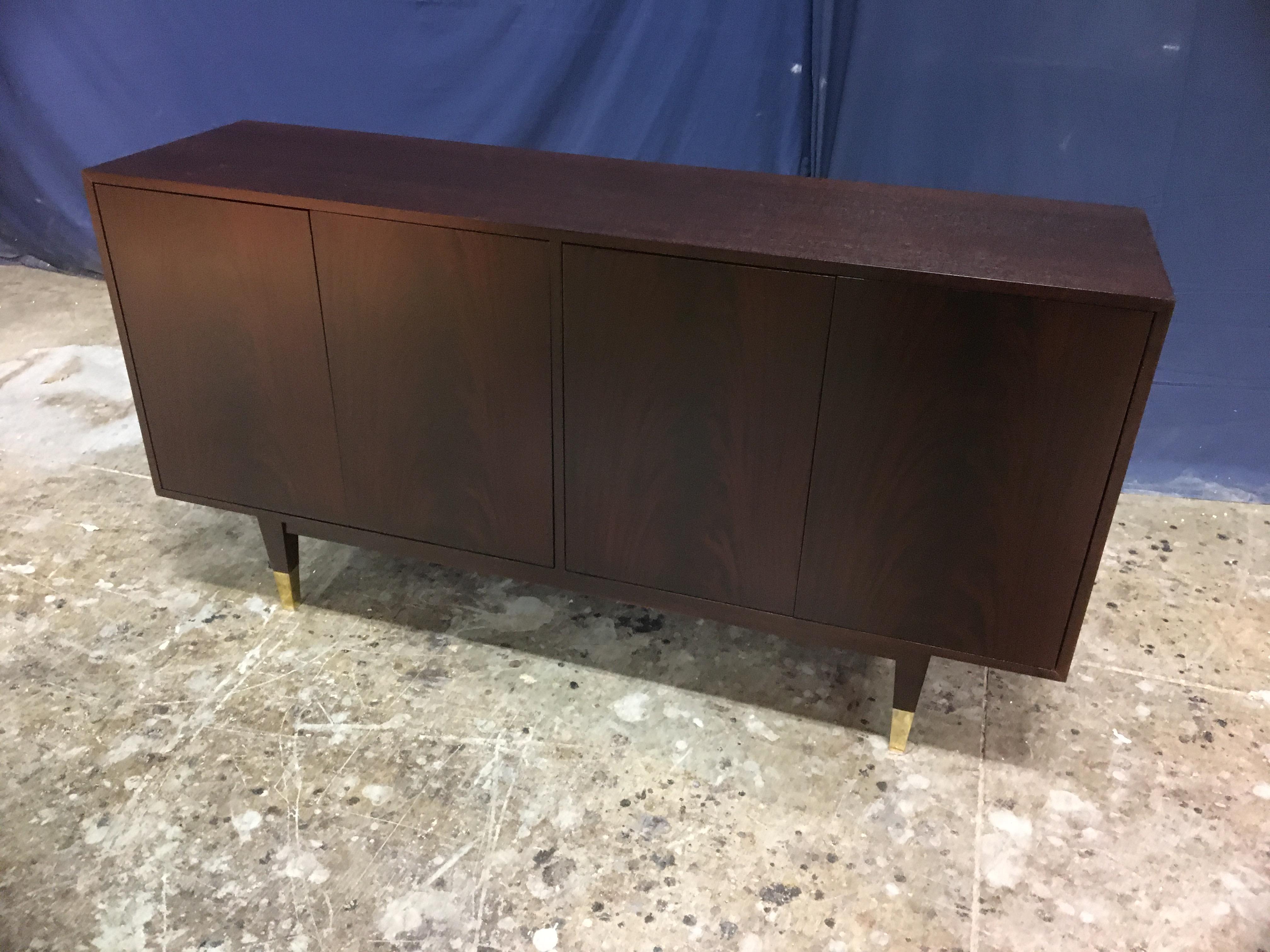 This is made-to-order midcentury style mahogany four door sideboard/credenza made in the Leighton Hall shop. It features four doors with swirly crotch mahogany and a top and sides of understated cathedral mahogany. It has square tapered legs which