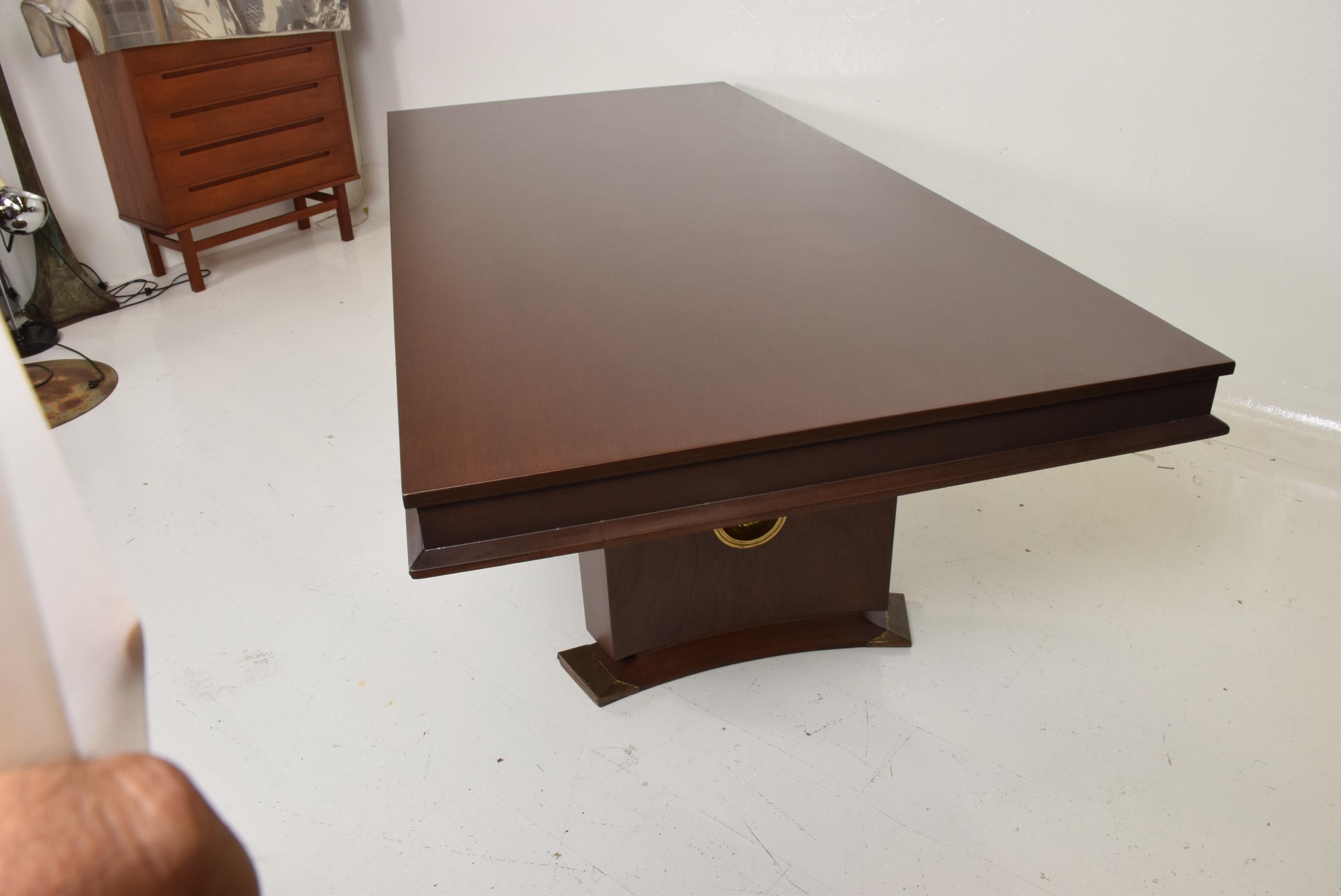 Stunning custom made mid-century Mexican modernist dining table in mahogany wood, with round patinated brass emblem on both sides of legs. Seats 8-10.  Includes two extensions.  
Made in Mexico City in the 1950's. 
Dimensions: 94.5 L x 43 3/8 W x 30