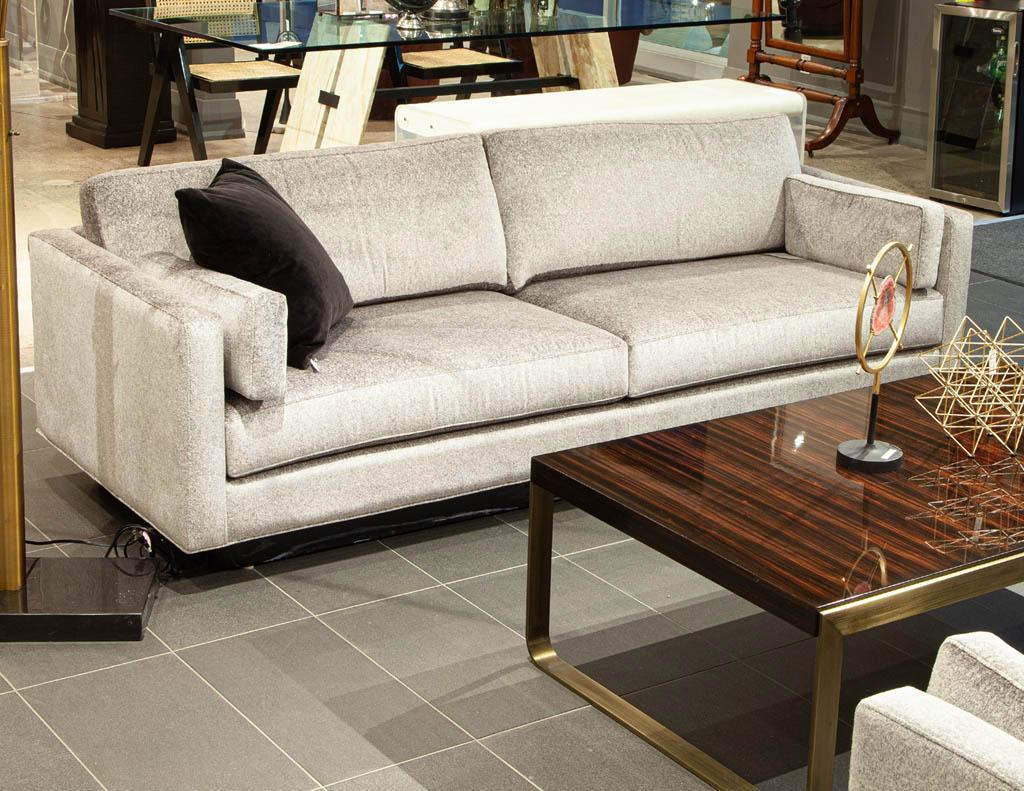 Custom Mid-Century Modern inspired sofa. Clean Mid-Century Modern design with thick back and seat cushions for comfort. Featuring a textured soft to the touch fabric in a silvery champagne color tone. Completed with a cerused oak black pedestal