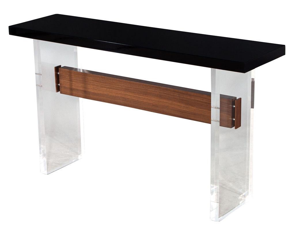Custom Modern Acrylic and walnut console table. Hand crafted and custom designed by Carrocel in Toronto, Canada, using the finest materials and techniques available. Composed of 2 large pieces of acrylic joined with natural walnut trestle. The top