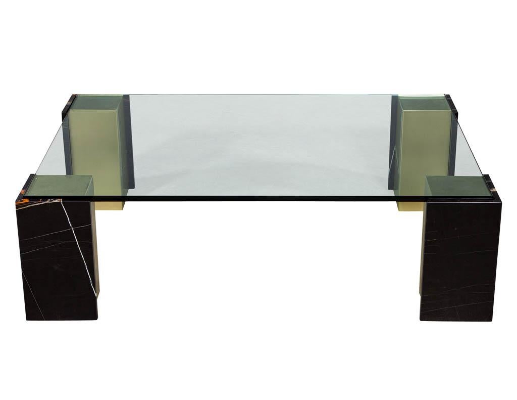 Custom modern glass top coffee table with marble pedestals by Carrocel. Sahara Noir stone clad with burnished brass pedestals topped with a generous glass top.

Price includes complimentary scheduled curb side delivery to the continental USA.
 