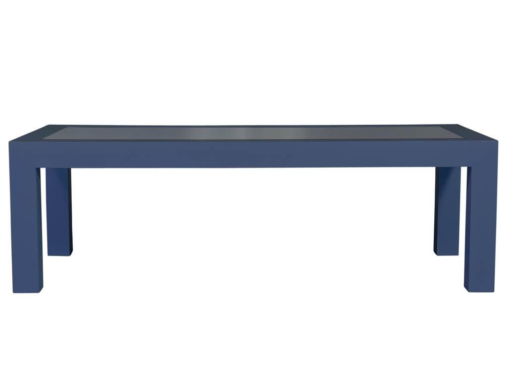 This modern dining table is a Carrocel custom piece. It is composed of solid wood finished in an indigo dark blue with an inlaid dark glass top surface. Sitting atop large square legs made the same size as the wood on all four sides of the tabletop,