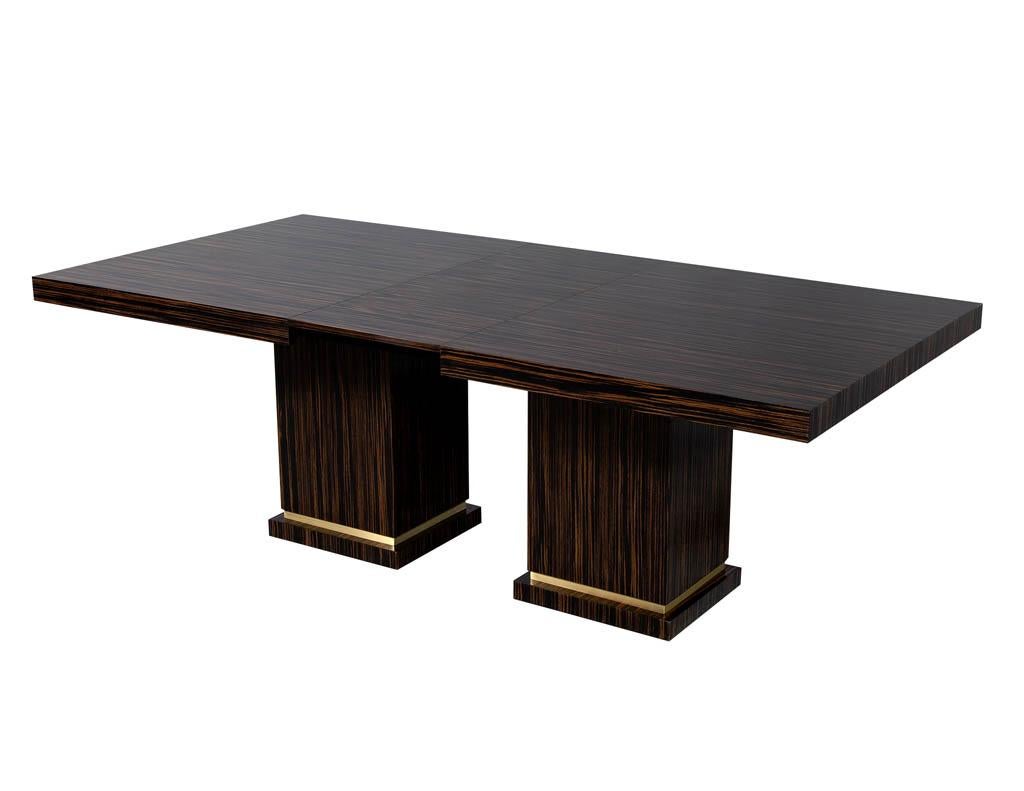 Custom modern Macassar dining table with Art Deco inspiration. Carrocel custom made dining table, modern sleek design with two pedestal columns accented with a brass detail. Table opens up for two table extensions which can be hidden in the centre