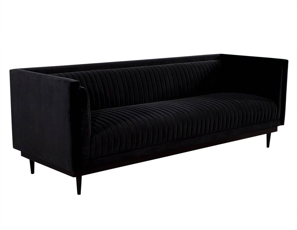 This modern sofa is made to order. Coated in a deep black fabric, it sits atop tapered satin black and tapered dark finished legs. Although the blue is luxurious. A perfect fit for a comfortable sitting room. Price includes complimentary curb side