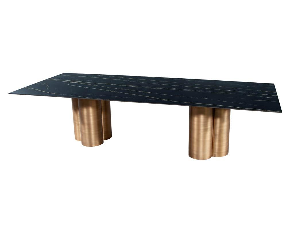 Custom Modern porcelain dining table with antiqued brass clover pedestals. Featuring beautiful veined Italian porcelain top with custom hand-crafted metal antiqued brass finished 3 column clover pedestals.
Due to the size and weight of this item