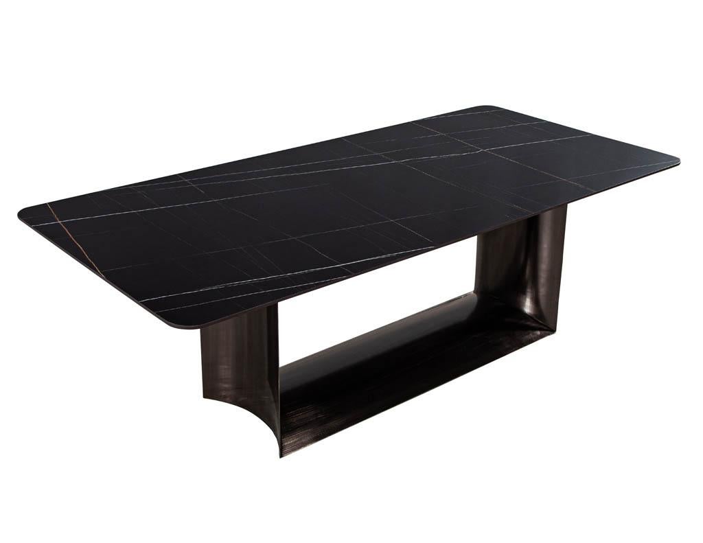 Table de salle à manger moderne sur mesure avec plateau en porcelaine et piédestal en métal incurvé. Avec son plateau en porcelaine noire aux coins incurvés et sa base géométrique arrondie en forme de canon fini bronze.

Le prix comprend la