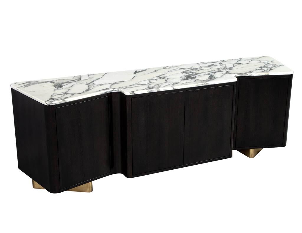 Custom modern serpentine styled marble top sideboard buffet media cabinet. Carrocel custom made, this Ceruse oak piece is a stunning example of artistry in furniture building. With a flowing curving design positioned on geometric gold leaf bases and