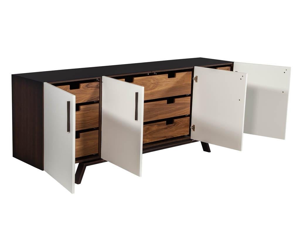 Custom modern walnut brass sideboard buffet by Carrocel. This modern sideboard buffet is made to order. The piece is finished in a light walnut satin with white front finish. It features four doors with three drawers on each end and three wider