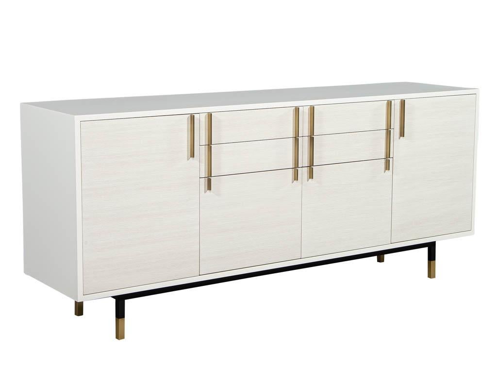 Custom modern white buffet sideboard by Carrocel. With a sleek design and simple brass hardware. Featuring beautiful wood grain fronts and a clean black base.
This is piece is custom, made to order. Price includes complimentary curb side delivery