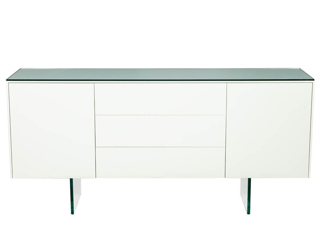 Individuelles, modernes, weiß lackiertes Sideboard-Buffet mit Glaselementen. Elegantes Sonderdesign von Carrocel, handgefertigt in Toronto, Kanada. Lackiert in zartem, satiniertem Weiß, mit Glasplatte und Sockeln.
Der Preis beinhaltet die