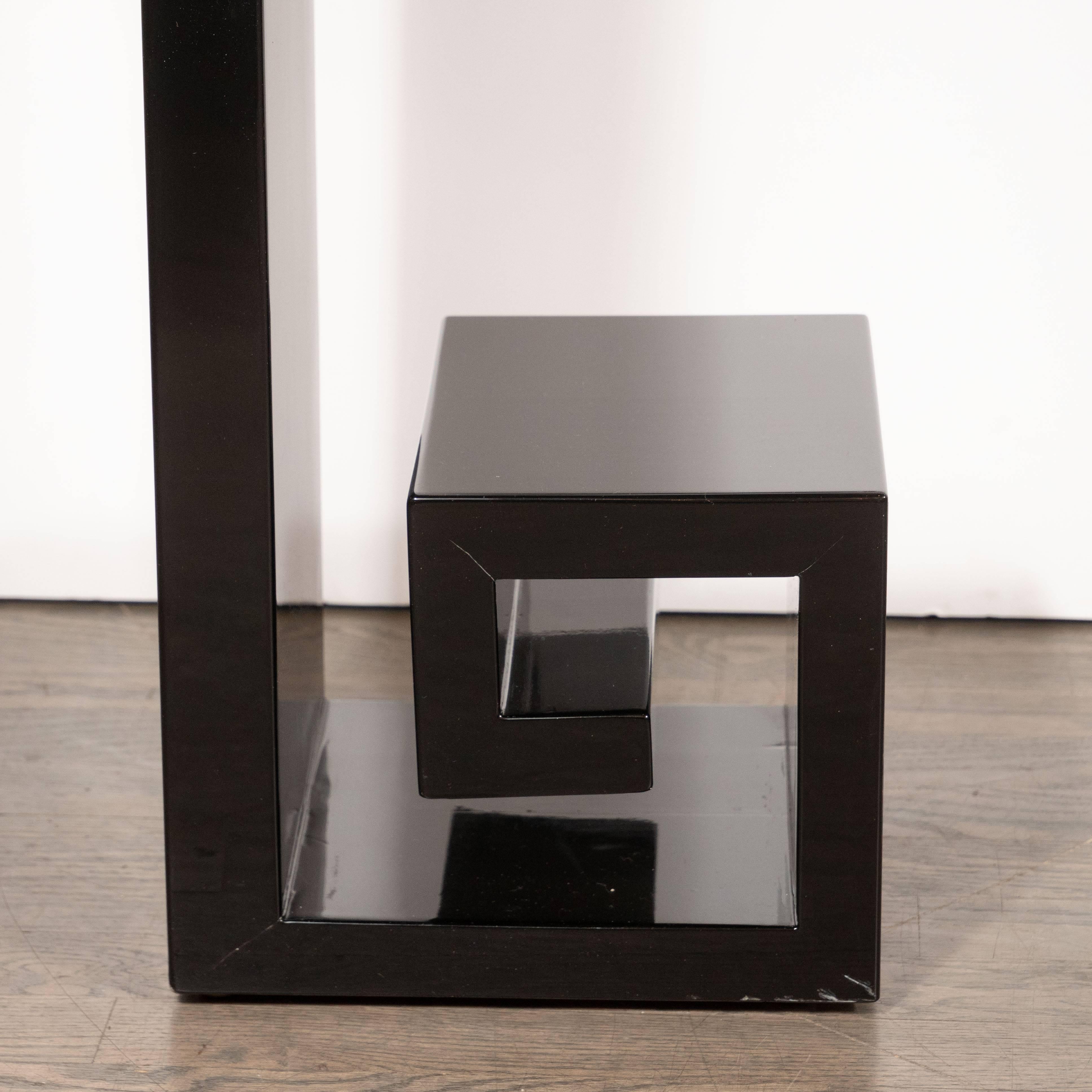This stunning modernist black lacquer console was realized by artisans in New York state. It offers an open square form with stylized Greek key detailing at its base and a rectangular drawer in its centre. With its classically inspired form and