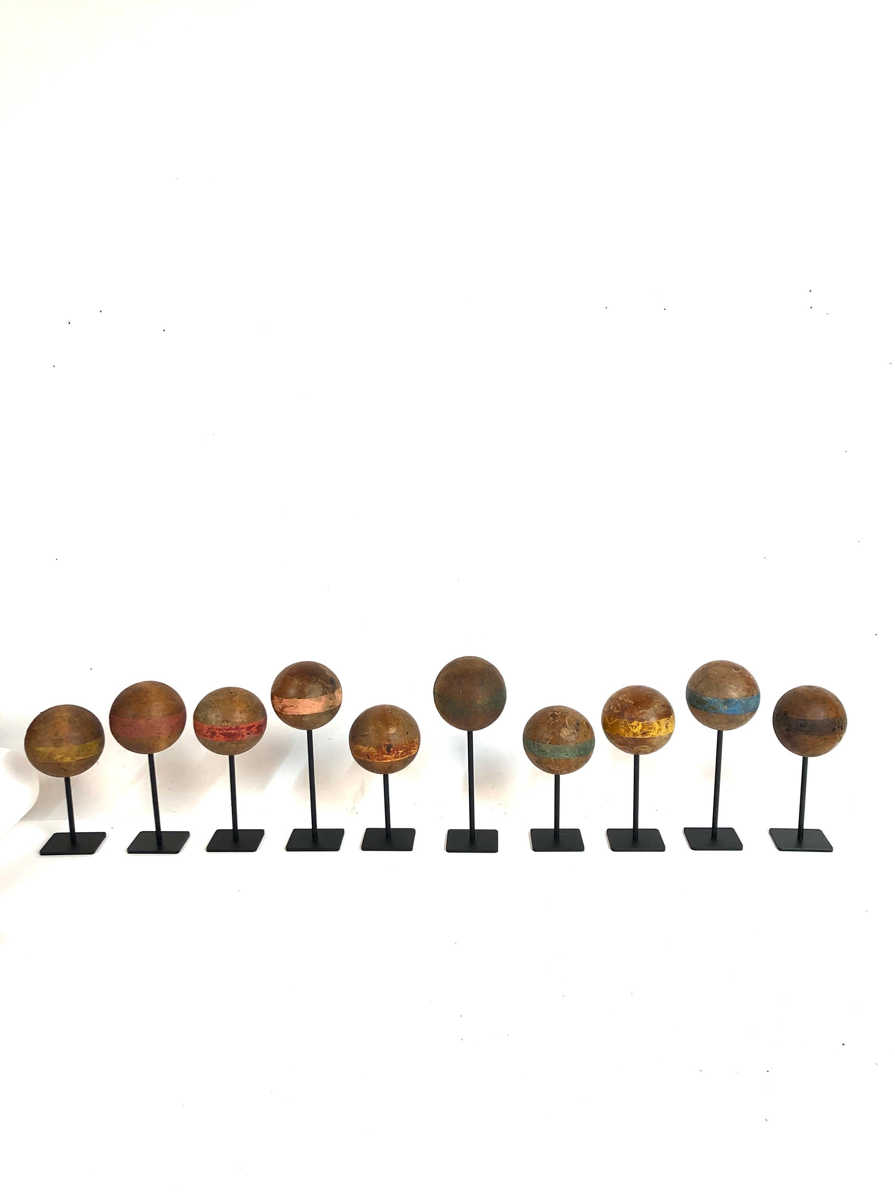 A collection of 10 custom mounted antique wood croquet balls. Black painted stands. The croquet balls have been waxed and polished. Range in size from 6.5