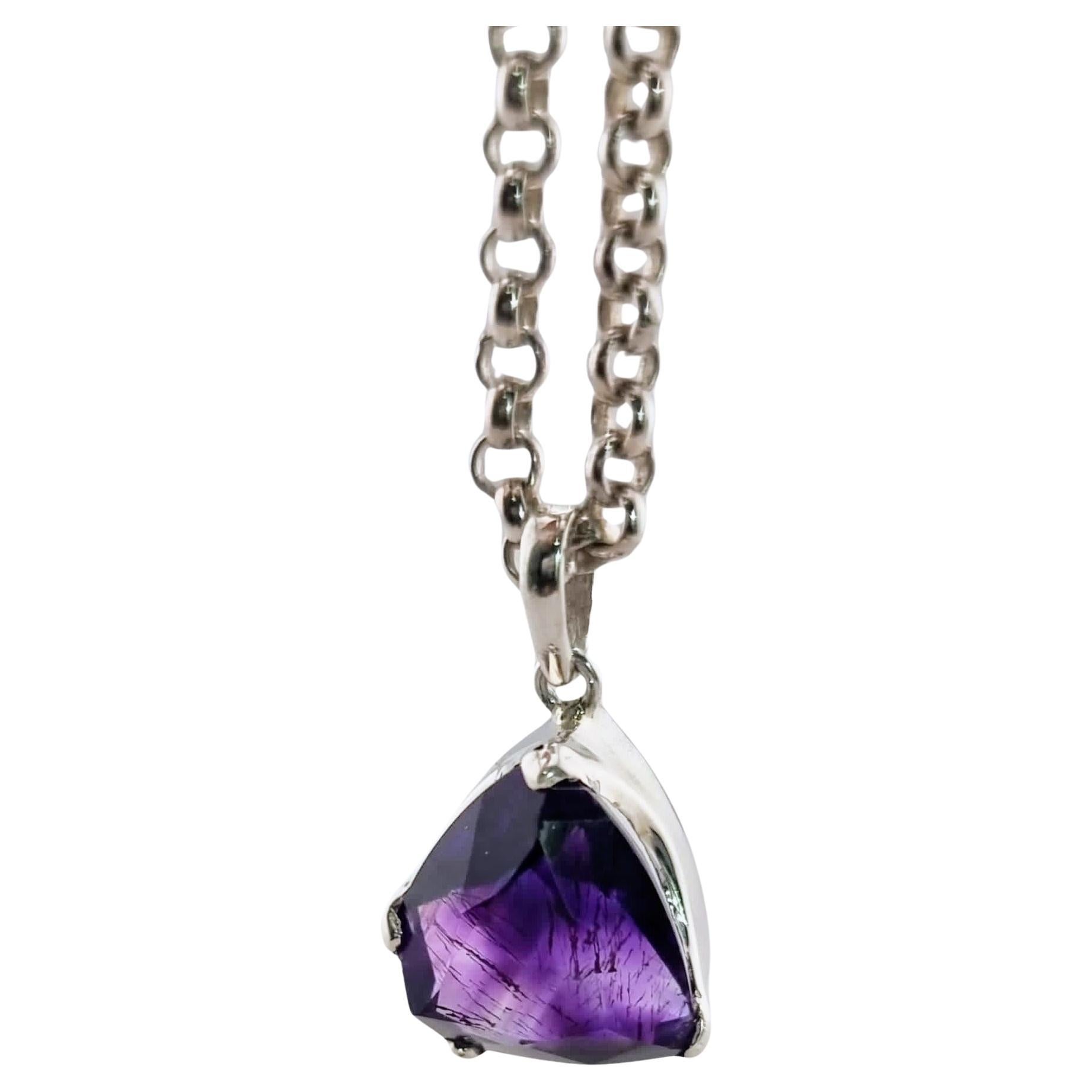 This pendant features a 16mm x 12mm custom cut amethyst, notable for its deep violet hue and precisely faceted design. The cut enhances the gemstone’s optical brilliance, creating an interplay of light and color that accentuates its natural beauty.
