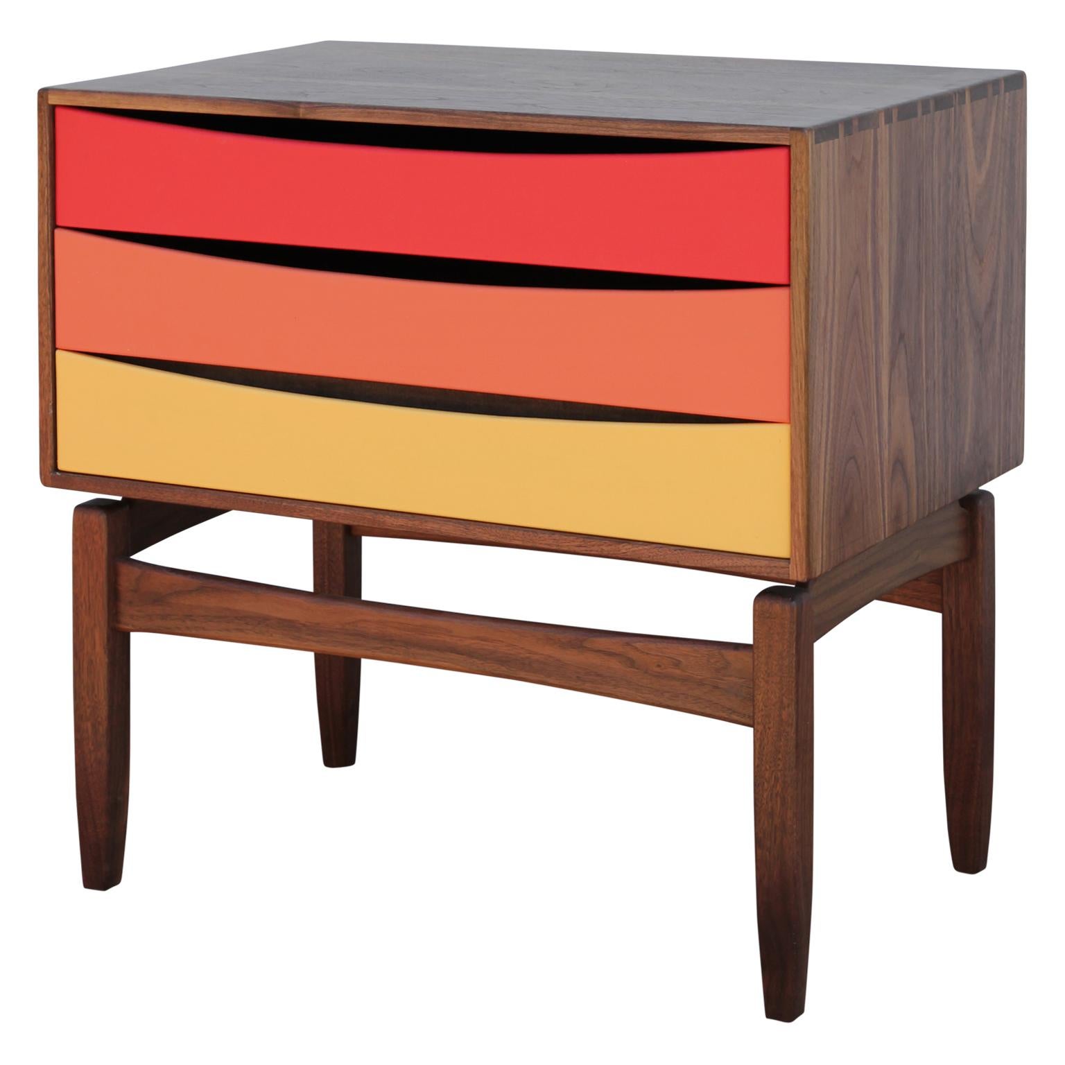 Custom three-drawer floating side table or nightstand by Norm Stoeker. The drawers are painted an ombre of red, orange and yellow and have a dovetail joint to the top. The wooden case is solid walnut. Features a rich grain and beautiful hand hewn