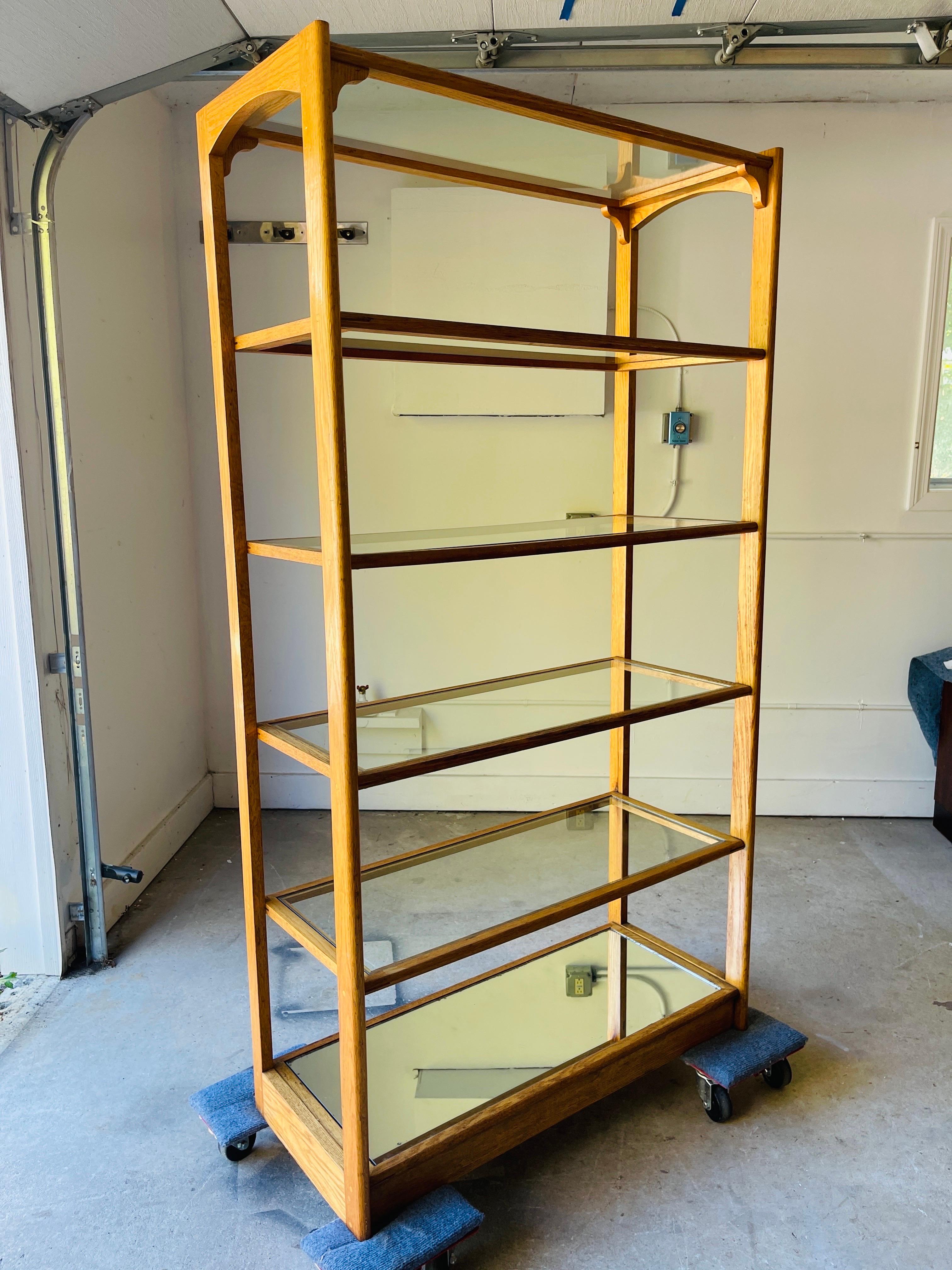 This beautifully crafted, custom-made oak shelf features five sturdy glass shelves and a mirrored base, perfect for showcasing your favorite decor, collectibles, or books. Its sleek design combines natural oak wood with the modern aesthetic of glass