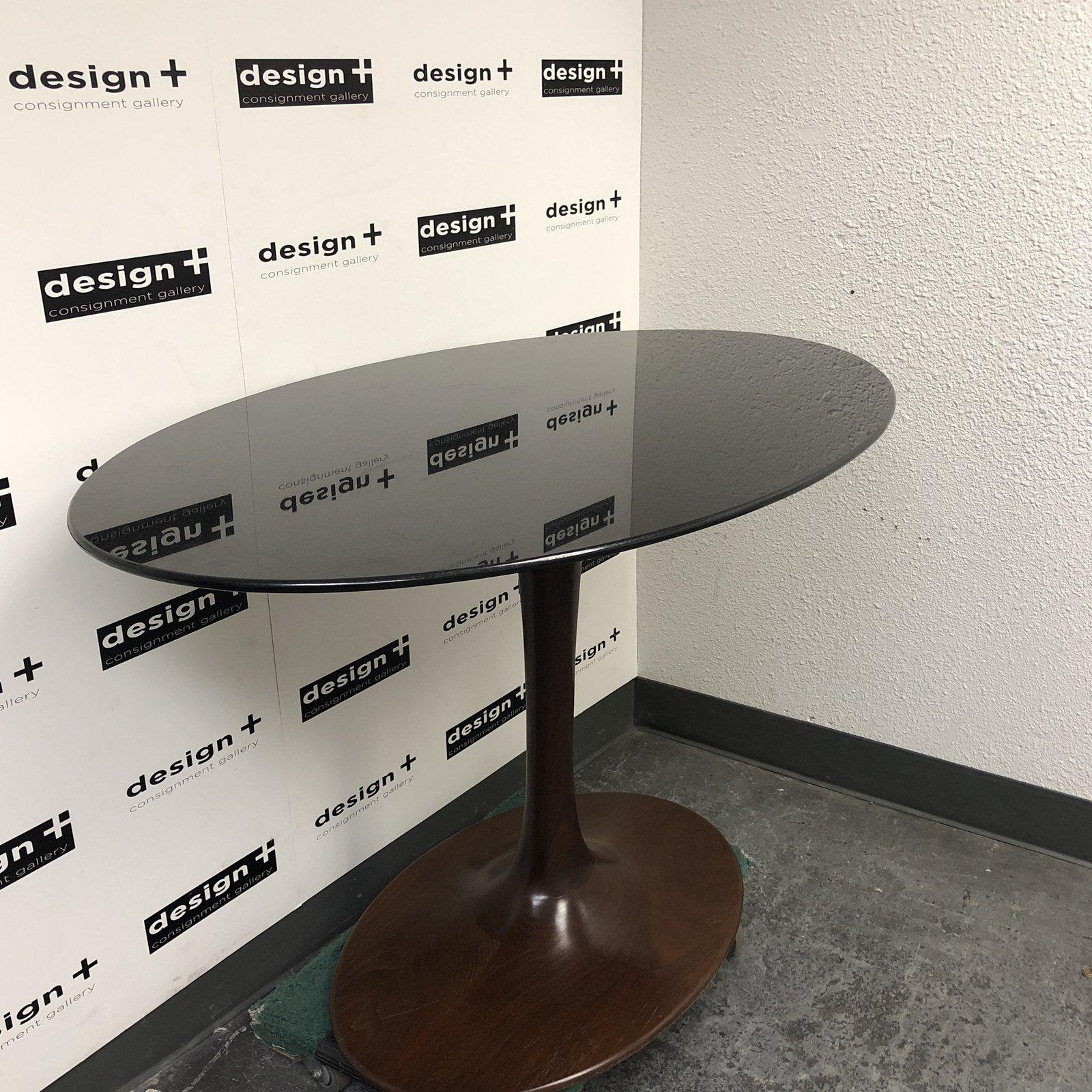 A custom midcentury style counter height table. Inspired by Iconic American designer Eero Saarinen Tulip table. The sleek curved base is wood in a dark walnut finish with minor wear. Accompanied with a oval polished edge black sapphire granite top.