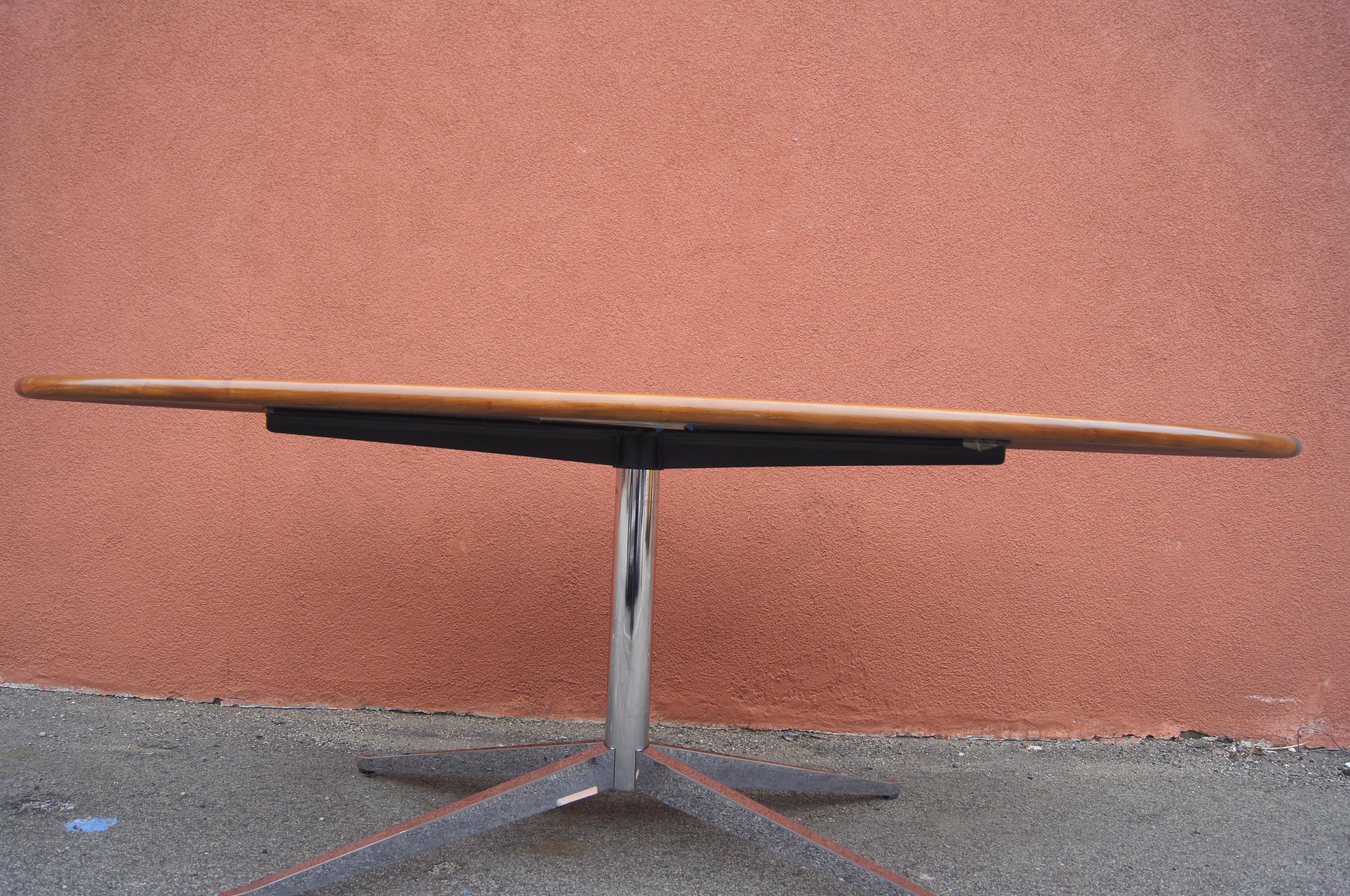This Florence Knoll table, or desk, is a custom version of her classic design from 1961. Sitting on a chrome pedestal four-legged base the oval walnut top features an unusual round edge. 

Label underneath.