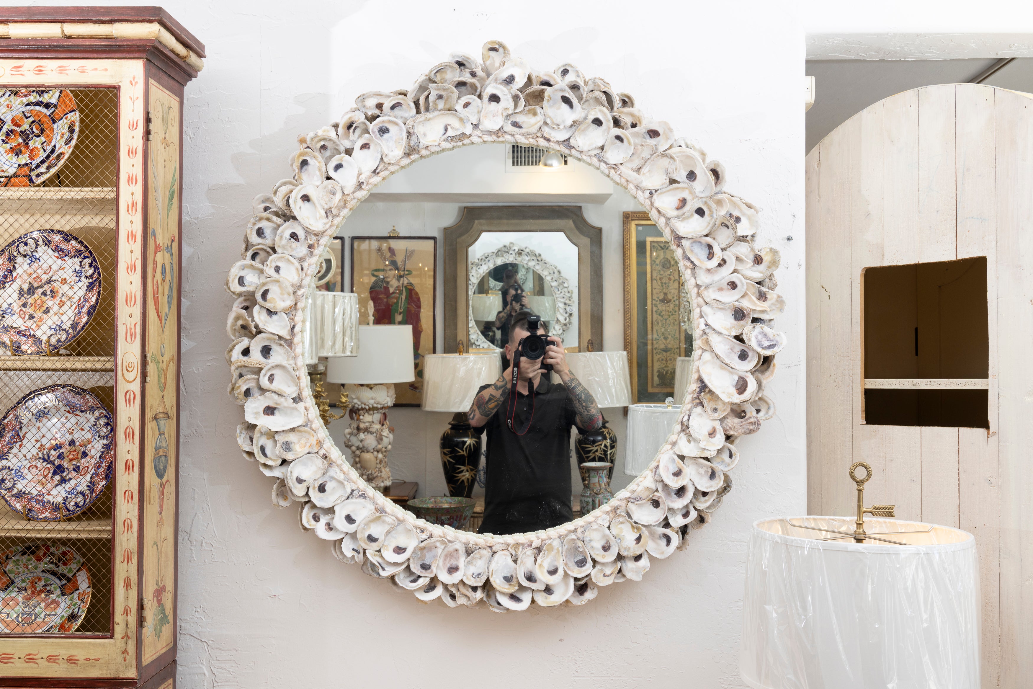 This is a decorative custom organic oyster shell mirror.  The circular frame is designed with clusters of oyster shells, encircling an interior mirror plate.