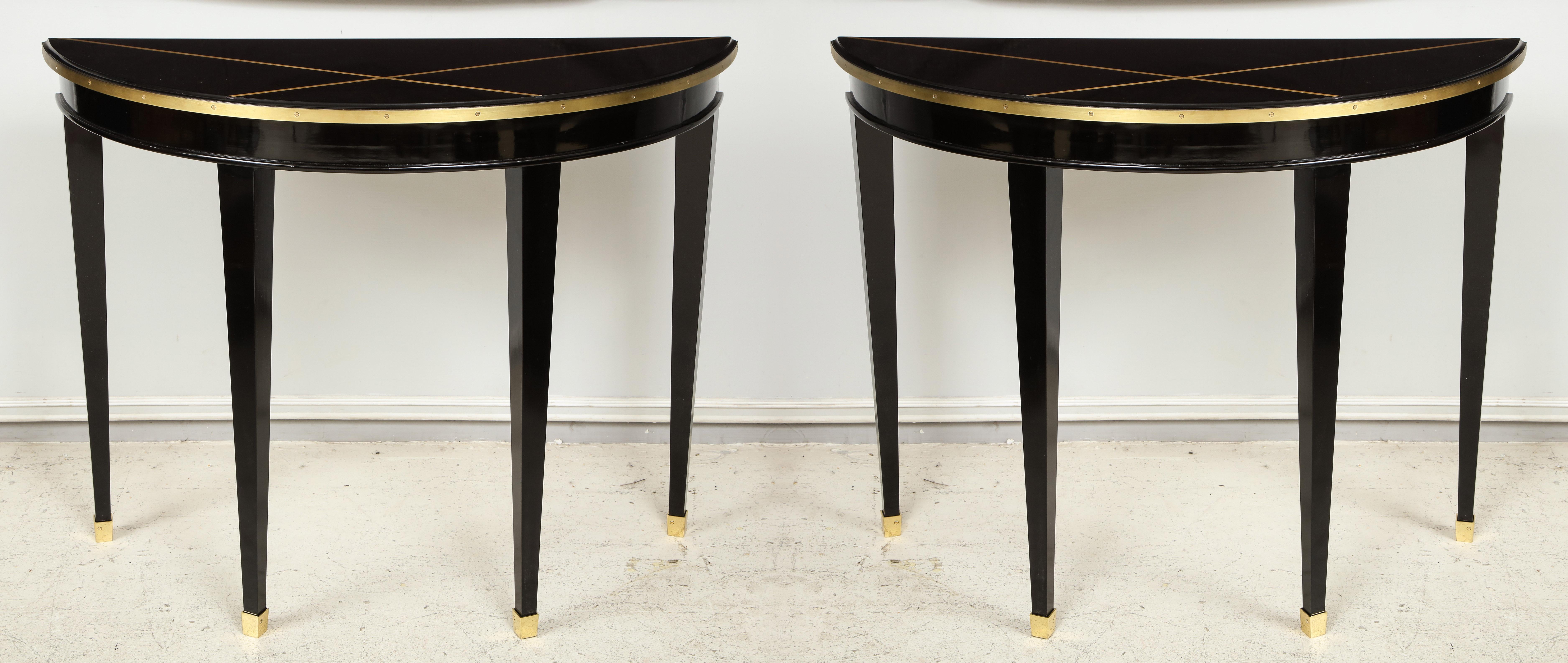 Custom pair of ebonized demilune consoles with inlaid brass top decoration on tapered legs ending in bronze sabots. These consoles can be customized to your specifications with a lead time of 8-10 weeks.