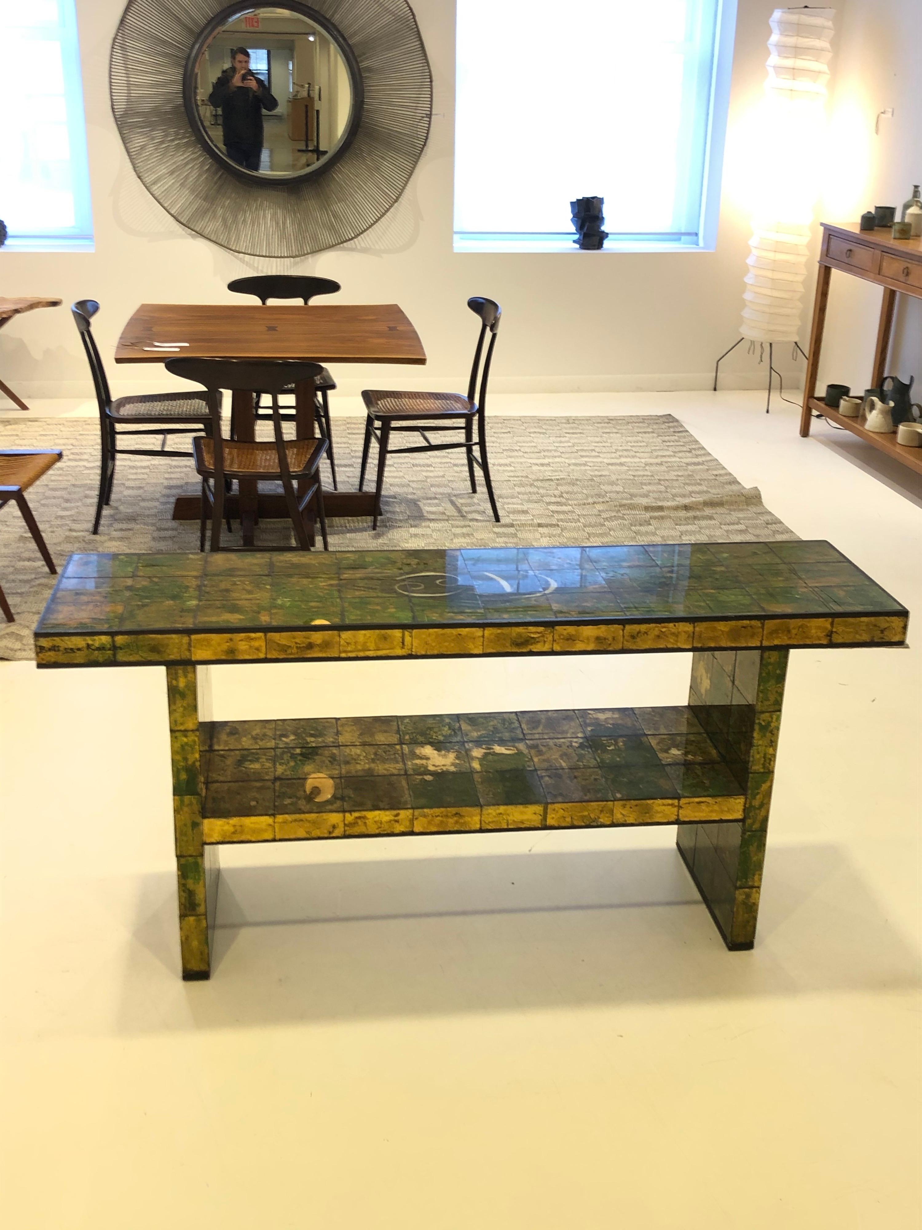 circa 1940, USA, the mosaic tile-clad two-tier table reverse painted in a gold leaf, green and black mottled abstracted design, by artist Karin van Leyden. A rare and elegant collaboration by the legendary Hollywood Society architect-designer and