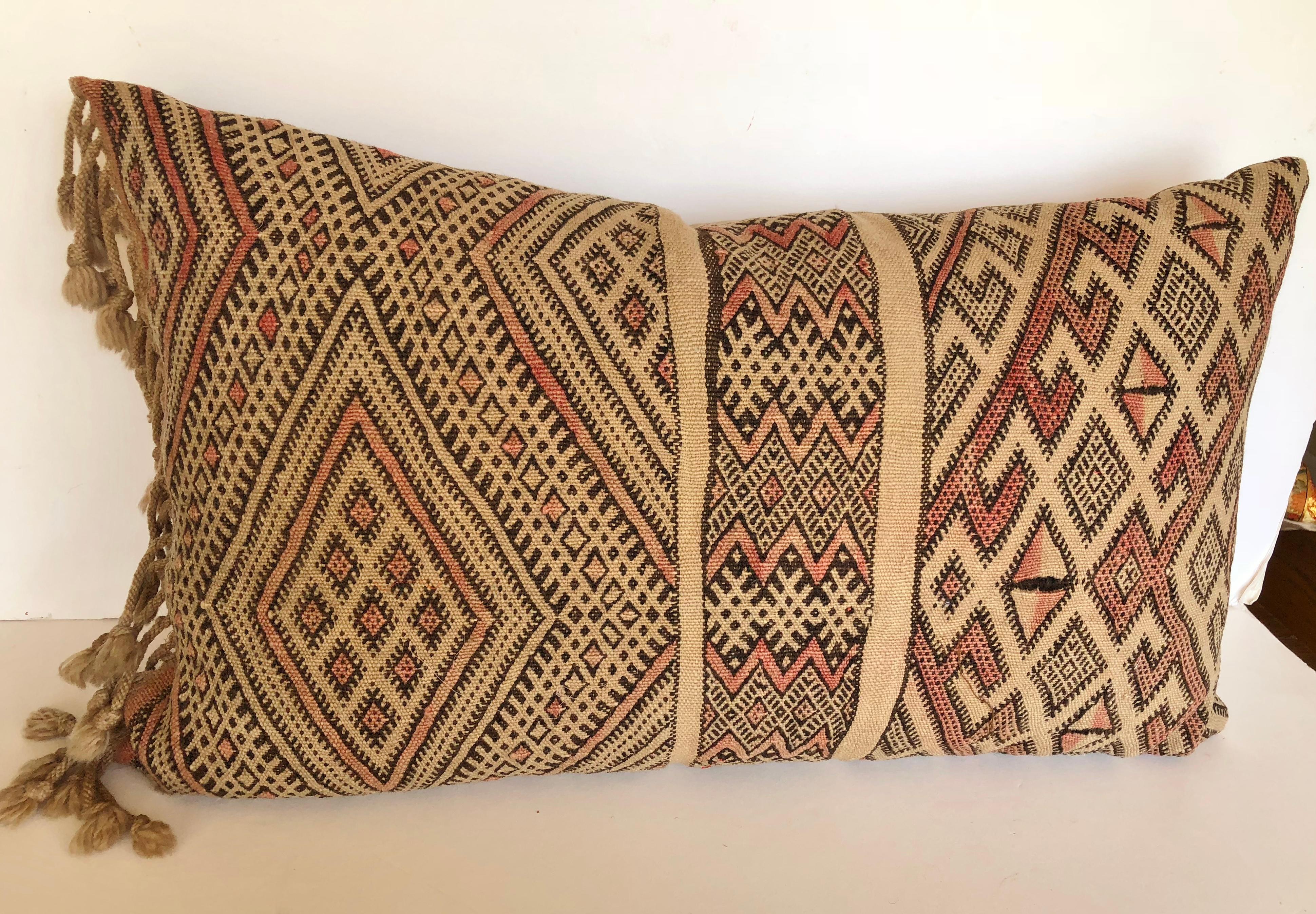 Custom pillow cut from a vintage hand loomed wool Moroccan Berber rug from the Atlas Mountains. The pillow incorporates the hand tied fringe that was originally on one end of the rug. It is backed in a silk/linen blend, filled with an insert of