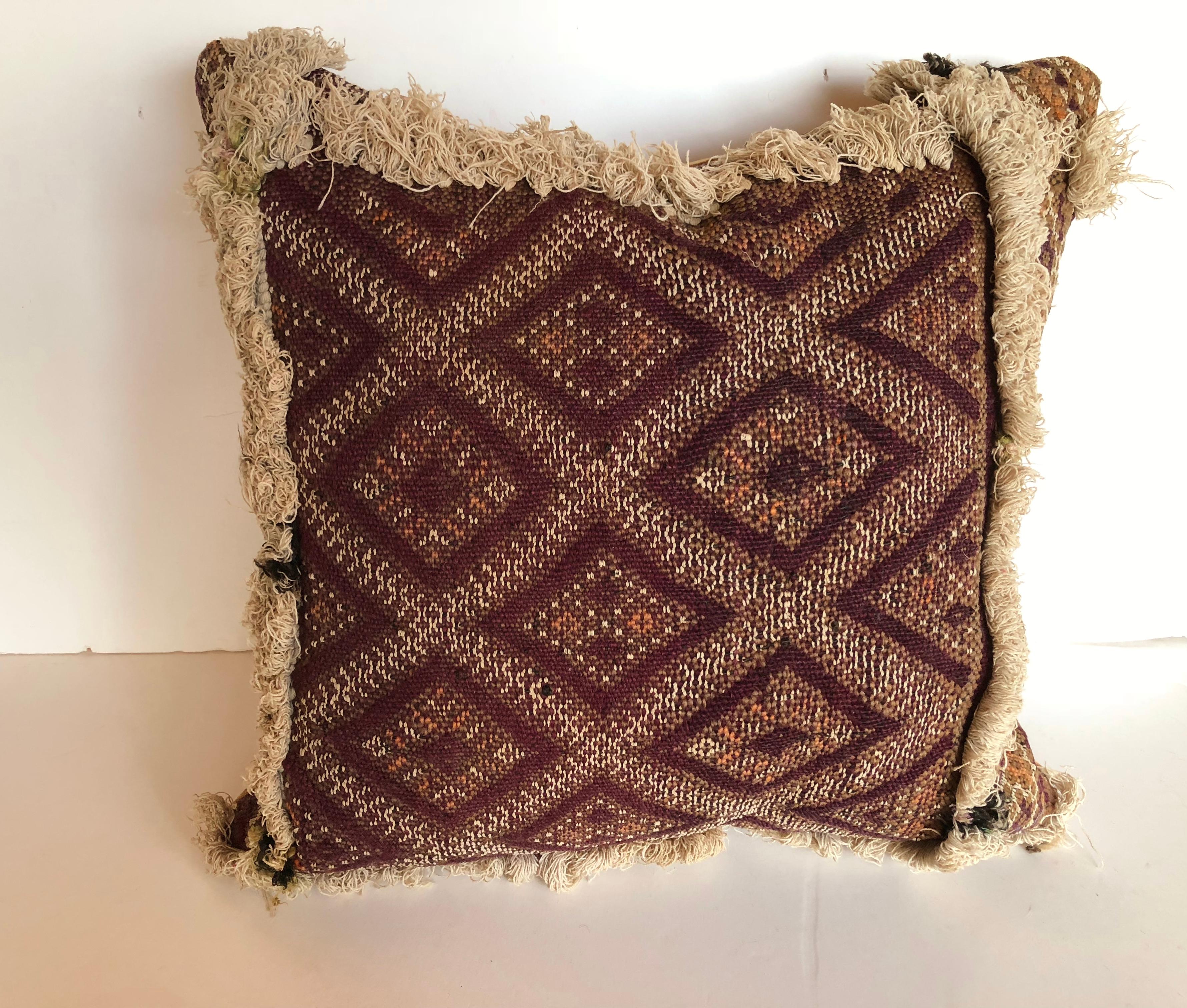 Custom pillow cut from a 100 year old hand loomed wool antique Moroccan rug from the Atlas Mountains. Each panel on the 20 ft long rug was a different design separated by ivory tufting. Rich colors in purple, orange, brown and ivory. Pillow is