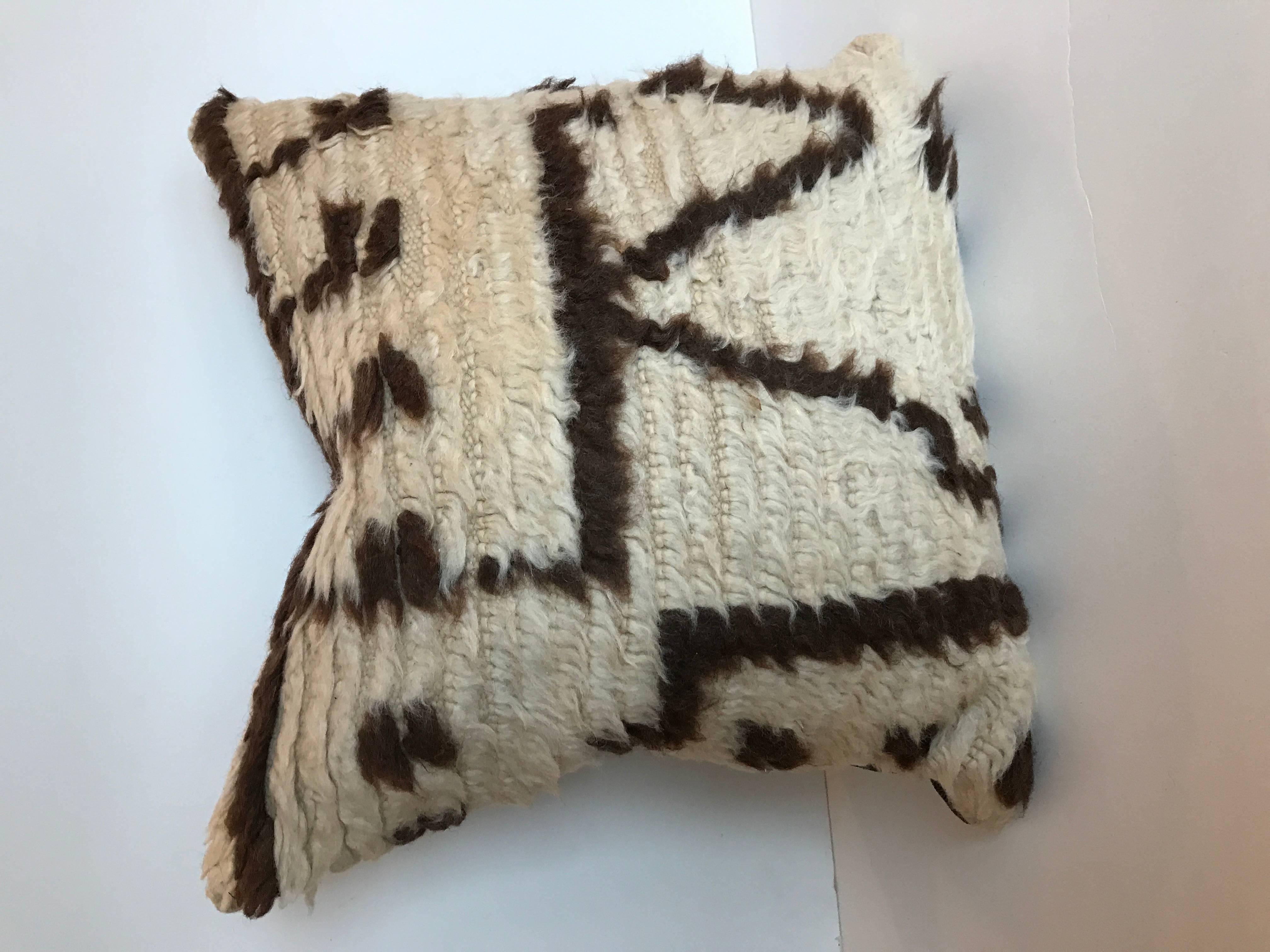 Custom pillow cut from a vintage hand loomed wool Moroccan Azilal rug made by the Berber tribes of the Atlas Mountains. The wool is soft and lustrous with natural colors and abstract tribal designs. The pillow is backed in a brown linen blend,