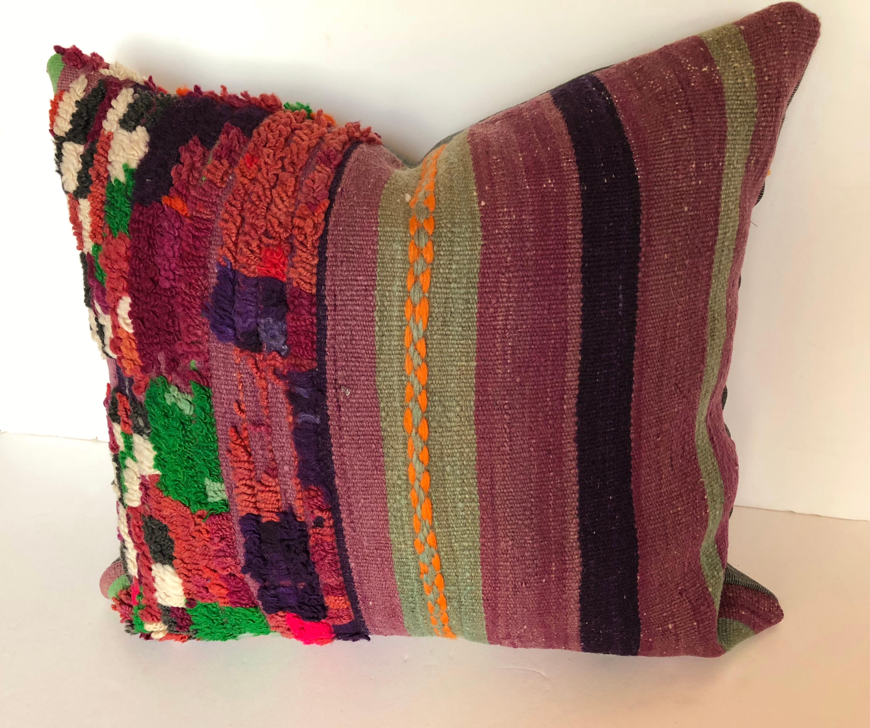 Custom pillow cut from a vintage hand-loomed wool Moroccan rug from the Atlas Mountains. Stripes in purple, green and gold with multi colored tufting on a purple base.
Pillow is backed in a dark teal silk, filled with an insert of 50/50 down and
