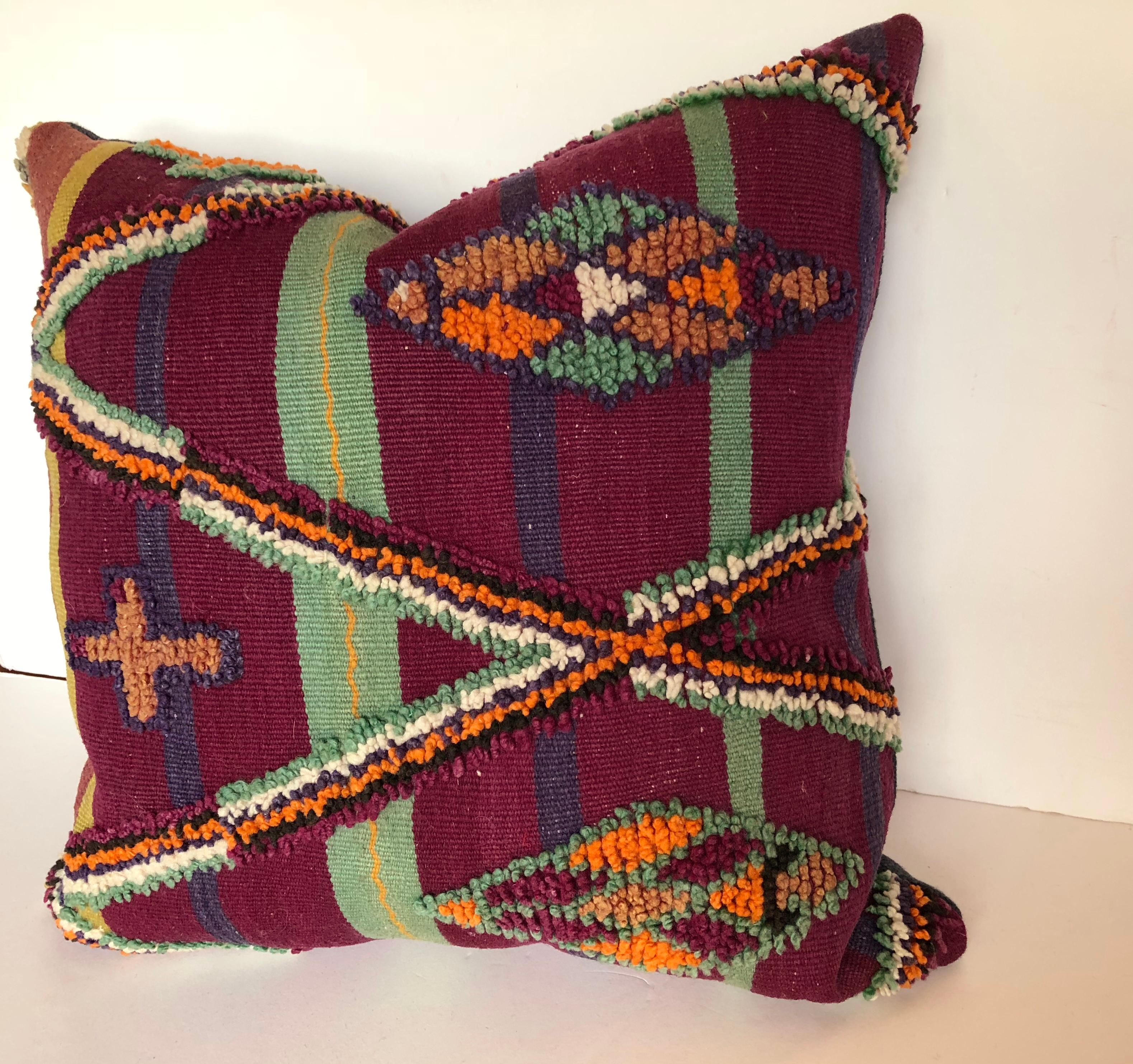 Custom pillow cut from a vintage hand loomed wool Moroccan Berber rug made in the Atlas Mountains. Wool is soft and lustrous with good color. Woven stripes are embellished with tufted tribal designs. Pillow is backed in a deep blue linen, filled