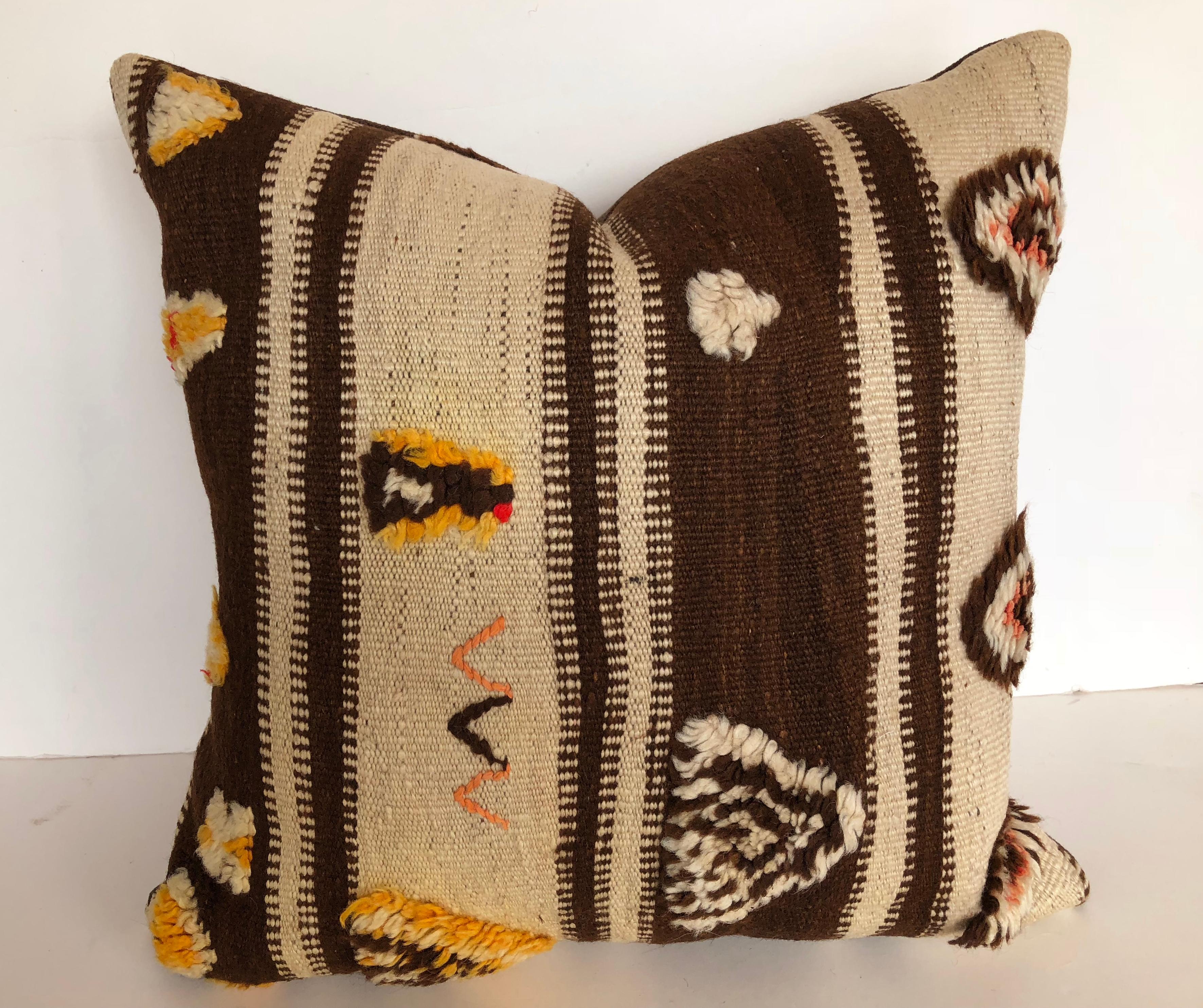 Custom pillow cut from a vintage hand loomed wool Moroccan Berber rug from the Atlas Mountains. Wool stripes are soft and lustrous with tufted wool tribal designs. Pillow is backed in dark brown linen blend, filled with an insert of 50/50 down and