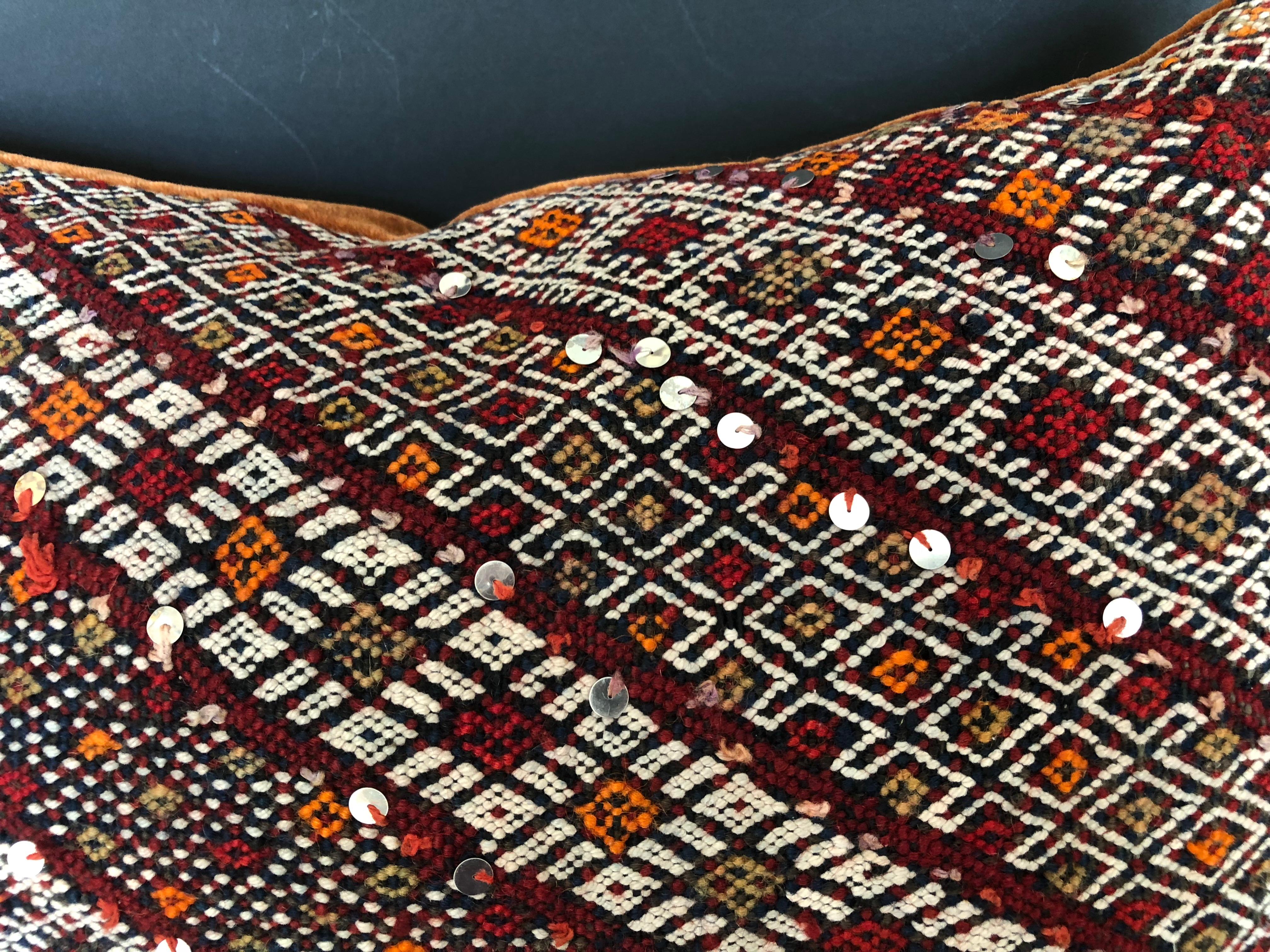 Custom pillow cut from a vintage hand loomed wool Moroccan rug from the Atlas Mountains. Tribal designs are embellished with sequins. Pillow is backed in a deep cinnamon mohair, filled with an insert of 50/50 down and feathers and hand sewn closed.