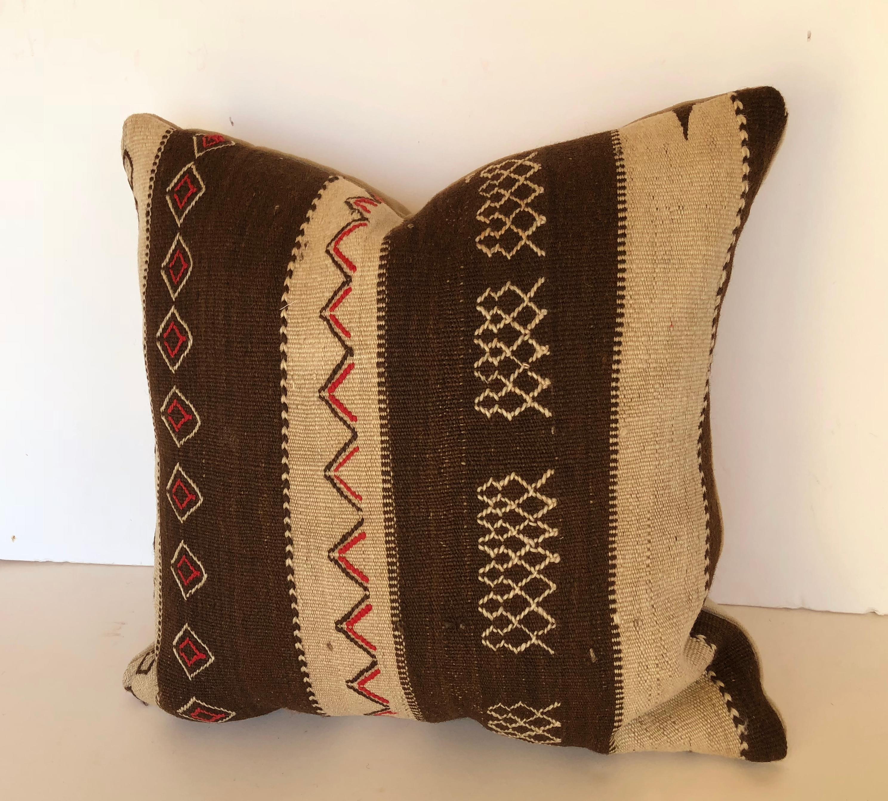 Custom pillow cut from a vintage Moroccan hand loomed wool Ourika rug made by the Berber tribes of the Upper Atlas Mountains. Wool is soft and lustrous with tribal embroidered designs. Pillow is backed in cream velvet, filled with an insert of 50/50