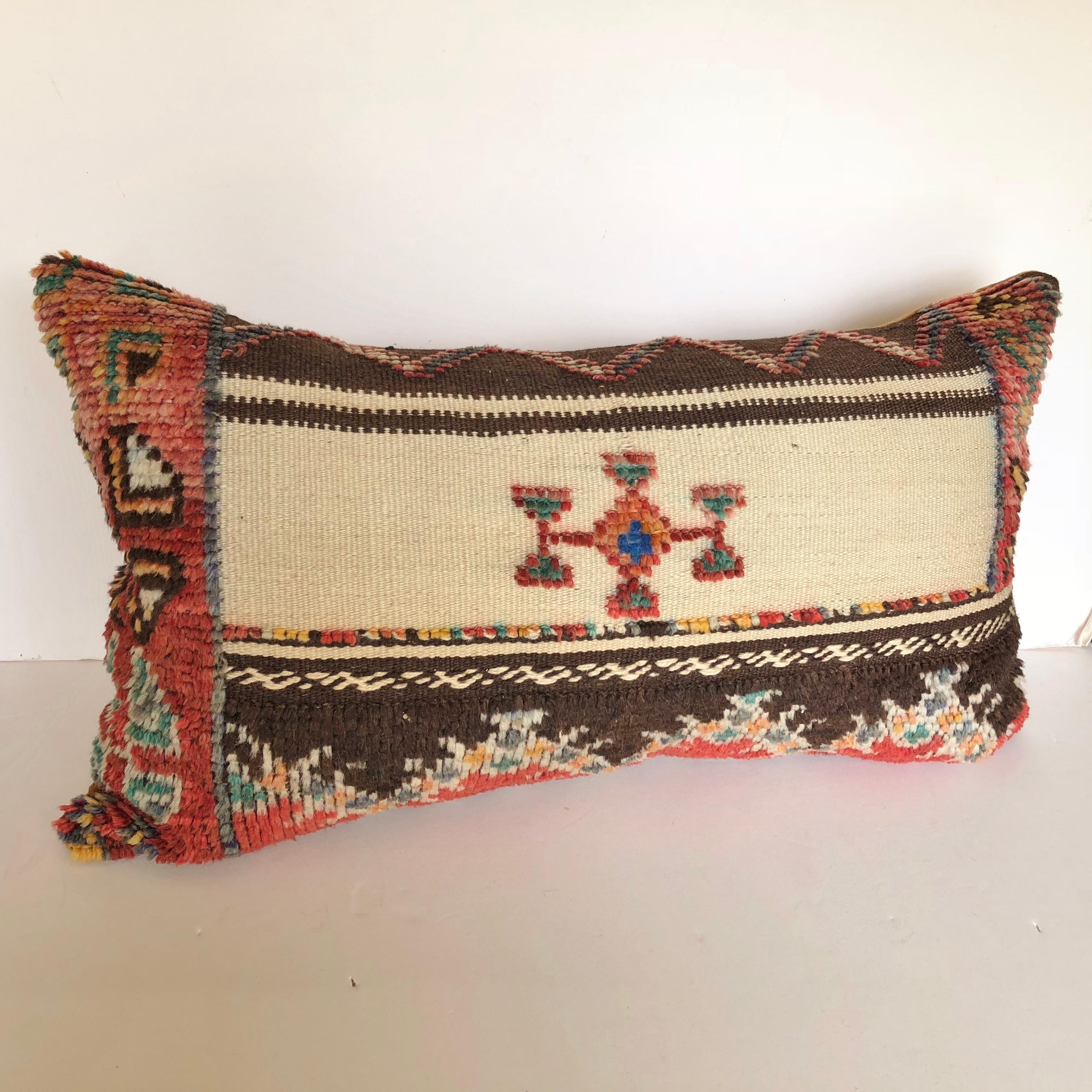 Custom pillow cut from a vintage hand loomed wool Moroccan Glaoui rug from the Atlas Mountains. Wool is soft and lustrous with tufted wool tribal designs over flat-weave stripes. Pillow is backed in velvet, filled with a 100% down insert and hand