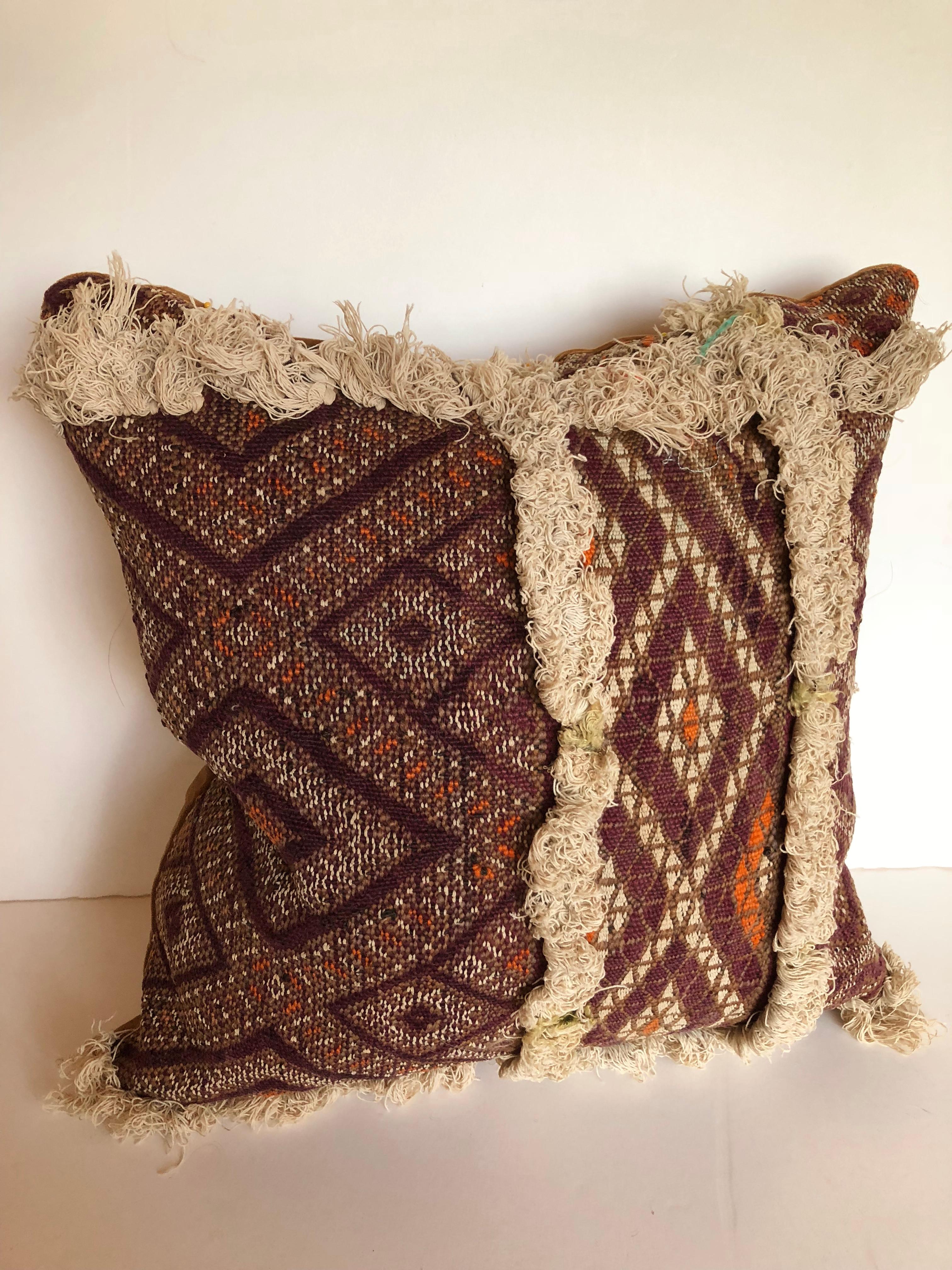 Custom pillow cut from a very rare antique hand loomed Moroccan wool textile from the Atlas Mountains. The wool sections are separated with rows of cotton and silk tufting, every section a different hand woven design. Pillows are backed in velvet,