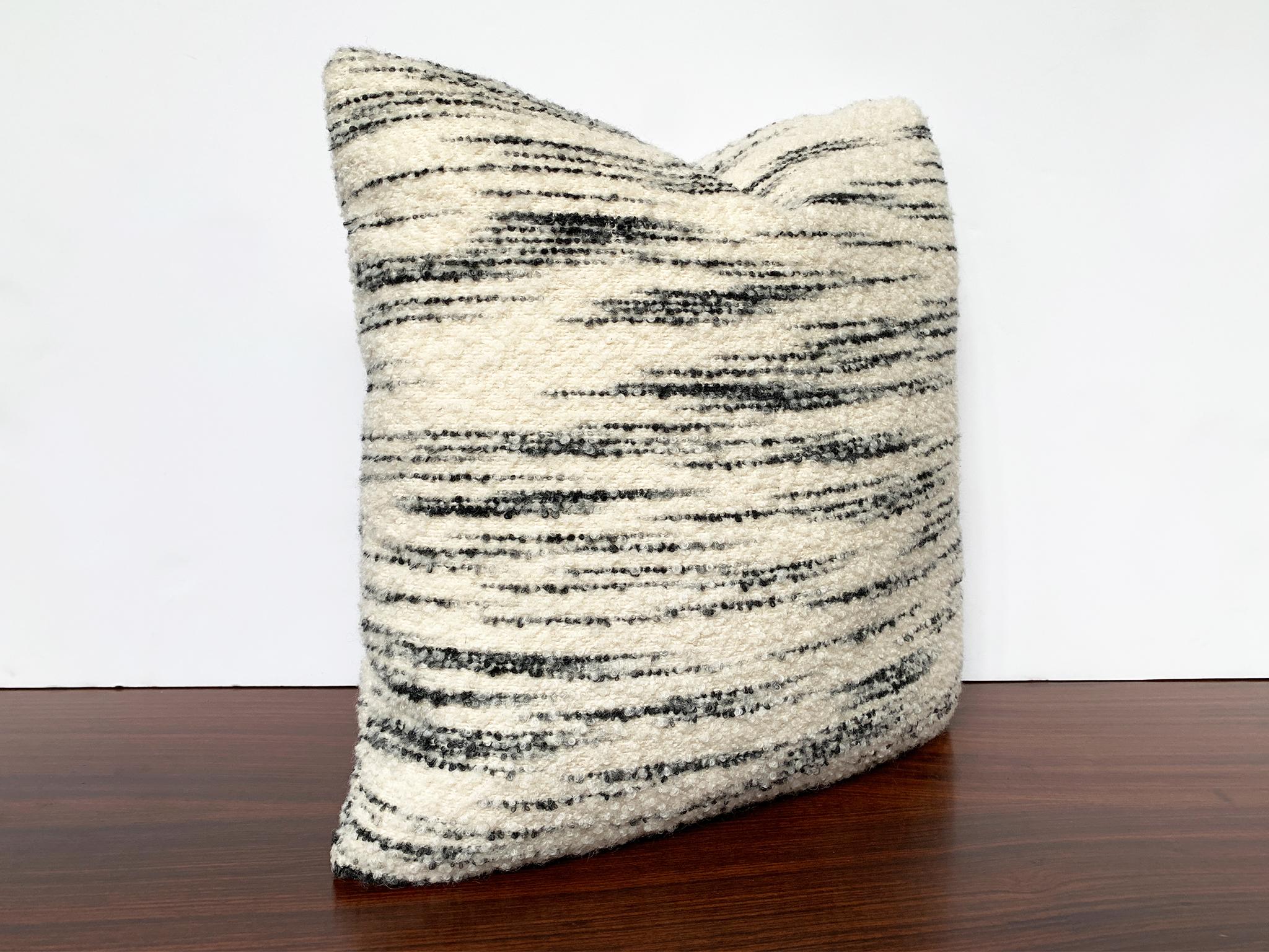 This new, custom made pillow is crafted from a soft wool bouclé made by Schumacher. The fabric is cream-white with horizontal black stripes and has a curly texture. The filling is a combination of foam and down. This is a very cozy pillow for your