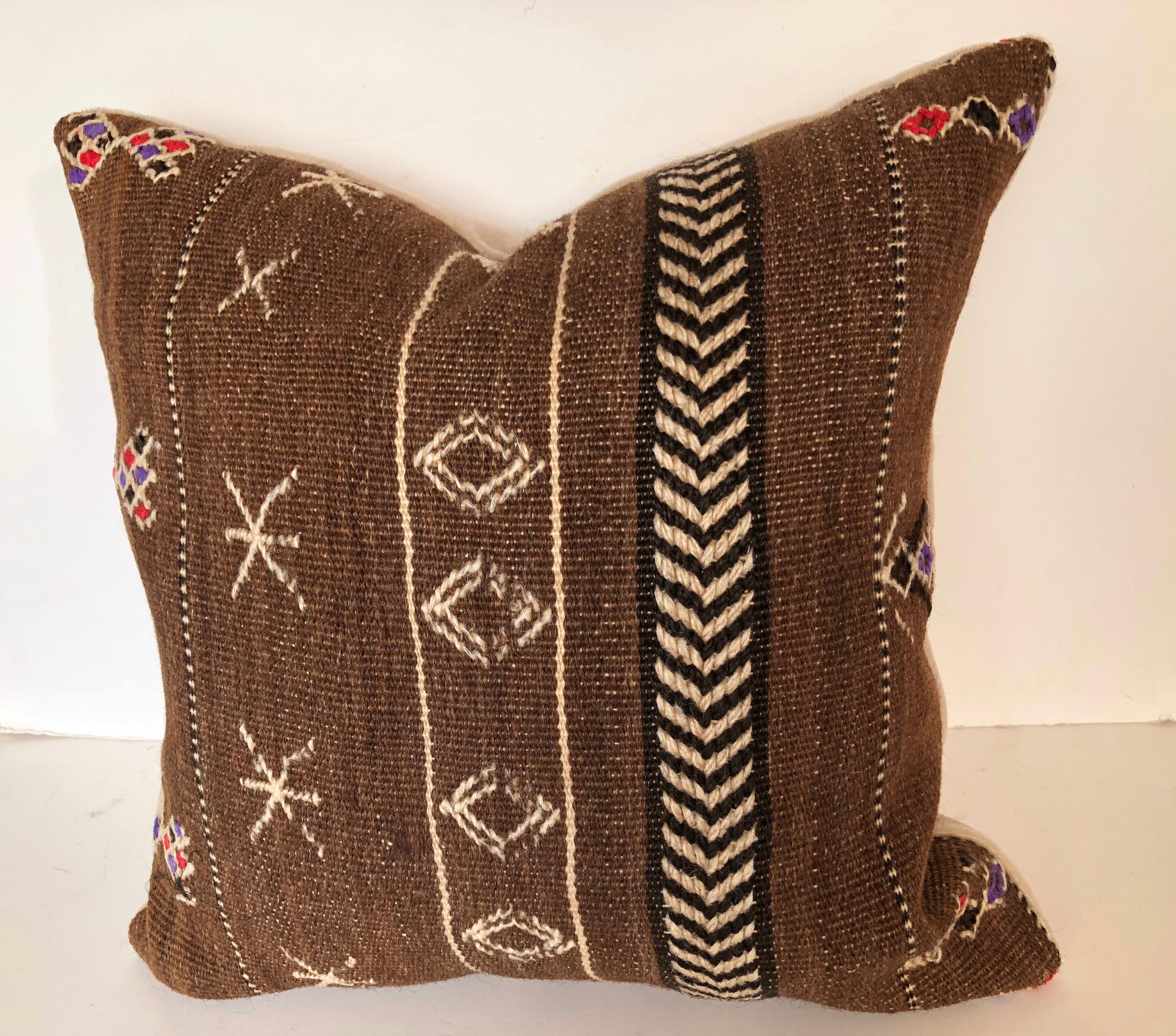 Custom pillows cut from a vintage hand loomed wool Moroccan Berber rug from the Ourika Valley in the Upper Atlas Mountains. Dark brown naturally colored wool has decorative tribal designs. Pillows are backed in cream mohair, filled with an insert of