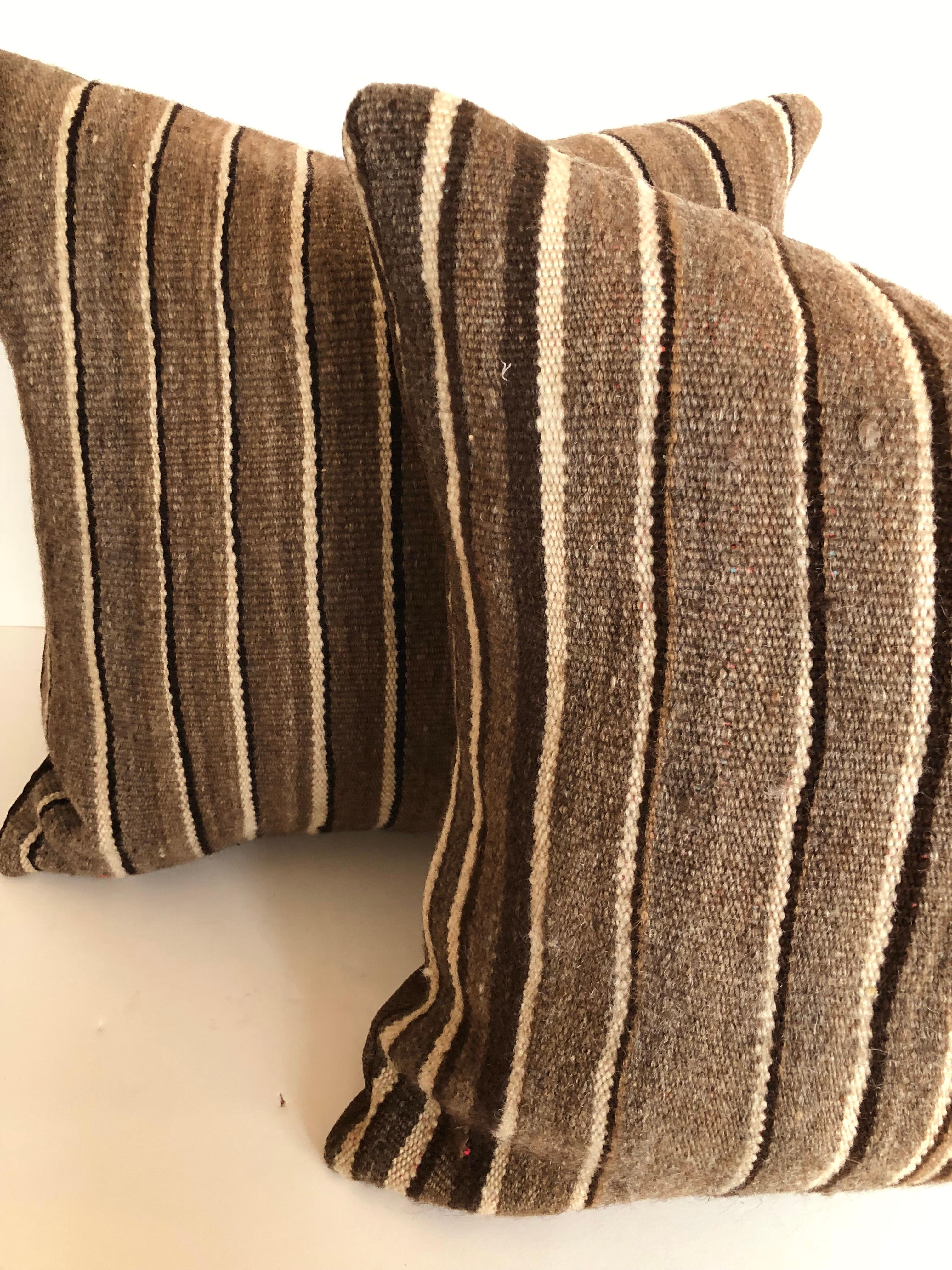 Custom pillows cut from a vintage hand loomed wool Moroccan Berber rug from the Atlas Mountains. Wool is soft and lustrous with stripes in shades of brown. Pillows are backed in dark brown linen blend, filled with inserts of 50/50 down and feathers