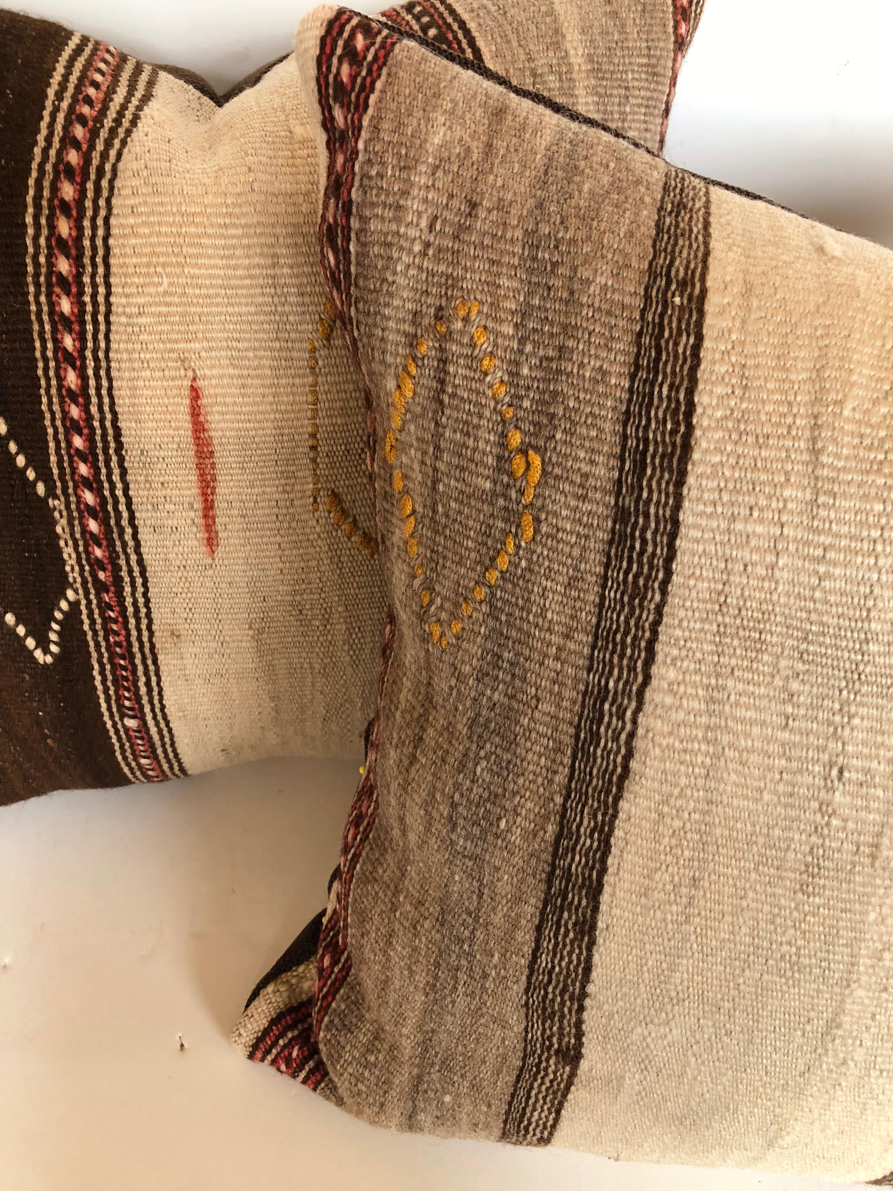 Custom pillows cut from a vintage Moroccan hand loomed wool Ourika rug from the Ourika Valley in the Atlas Mountains. Wool is soft and lustrous with stripes in natural colors and embroidered accents. Pillows are filled with an insert of 50/50 down