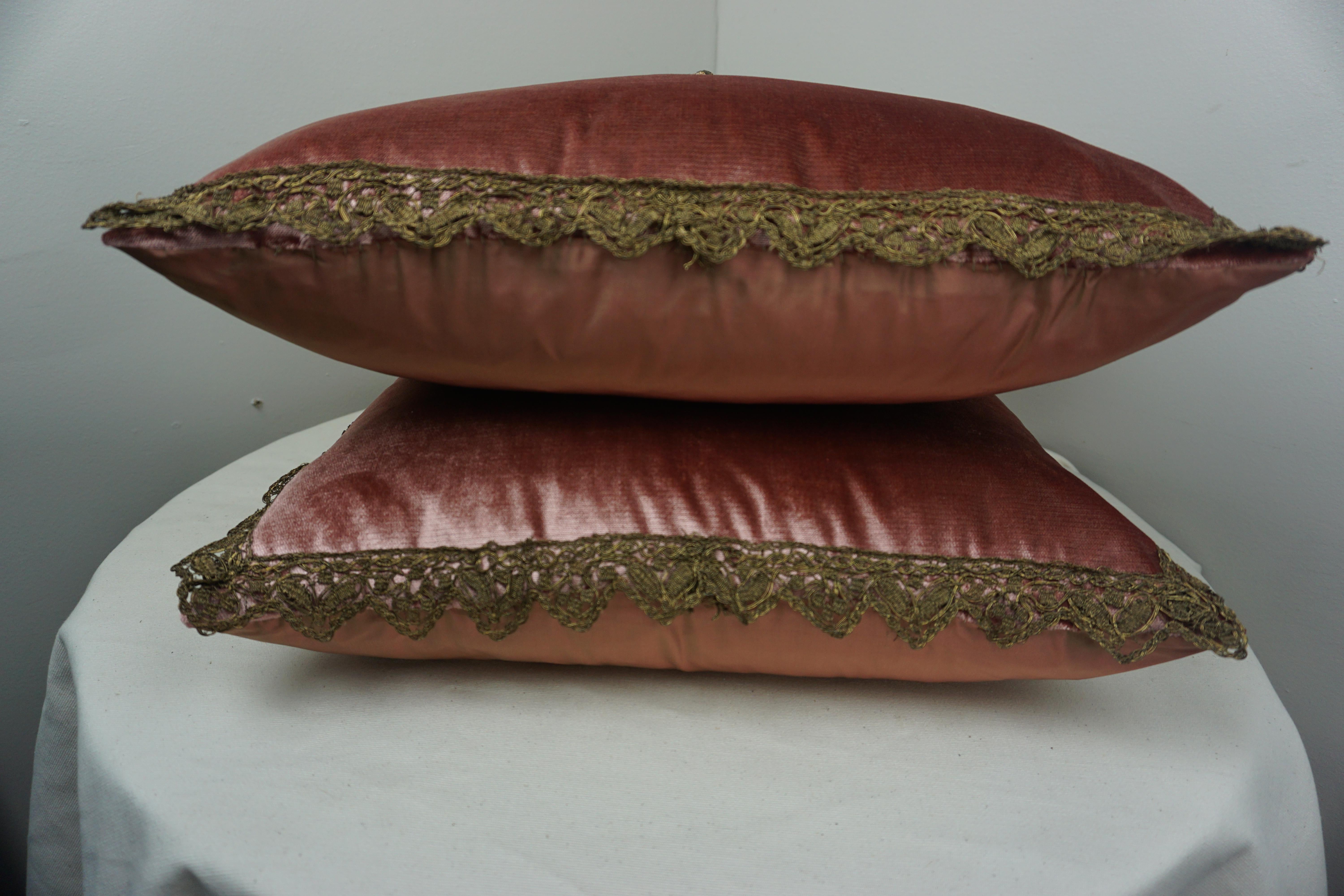 Pair of custom pillows made with 19th century French metallic and chenille appliques hand sewn on pink velvet fronts with pink silk backs. 19th century metallic trim around the perimeter of both pillows. Down inserts, sewn closed.