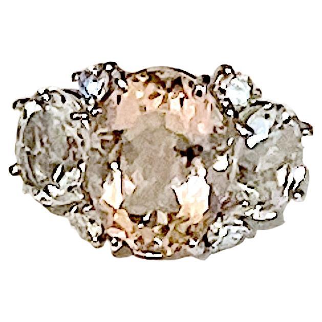 Custom Platinum Three stone Ring with center faceted oval Morganite weighing approximately 8.00 cts with two oval faceted Rock Crystal weighing approximately 3.00 cts each accented with four round brilliant Diamonds weighing approximately 0.60cts